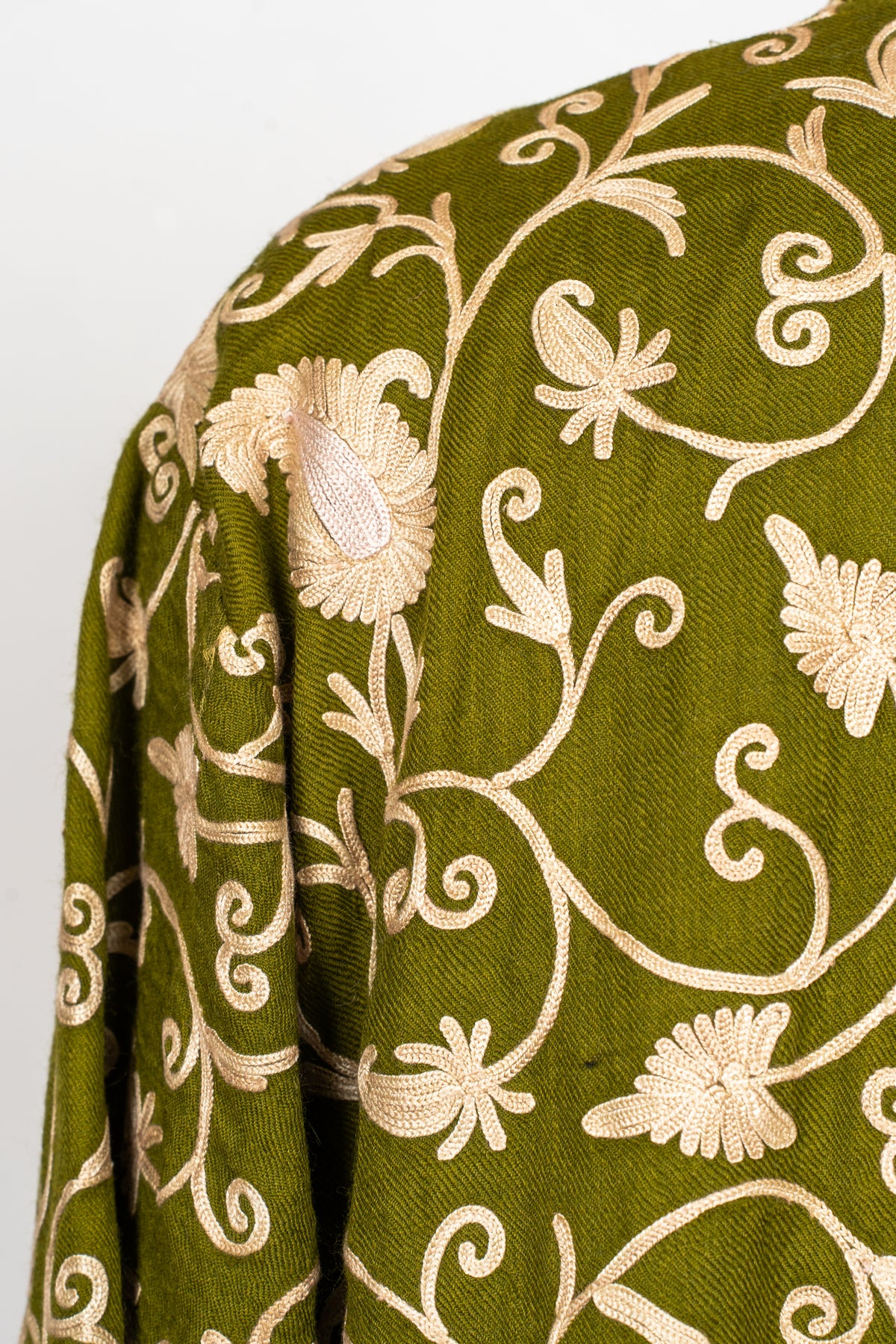 Close-up of the olive abaya’s shoulder showing raised beige floral Aari stitching and curling vines