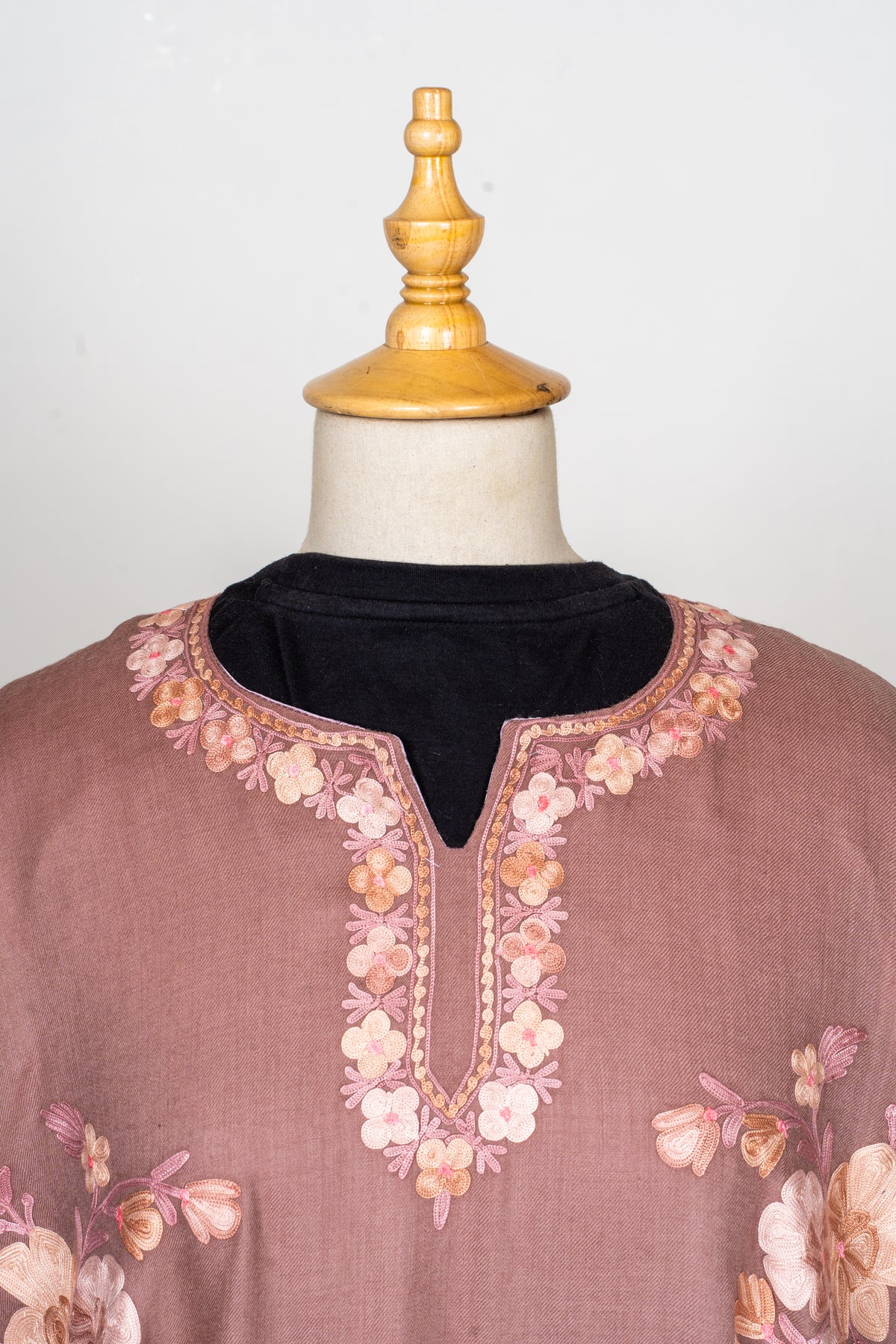 Close-up of the notched neckline of a dusty rose abaya, edged with pale pink, ivory and peach Aari flowers