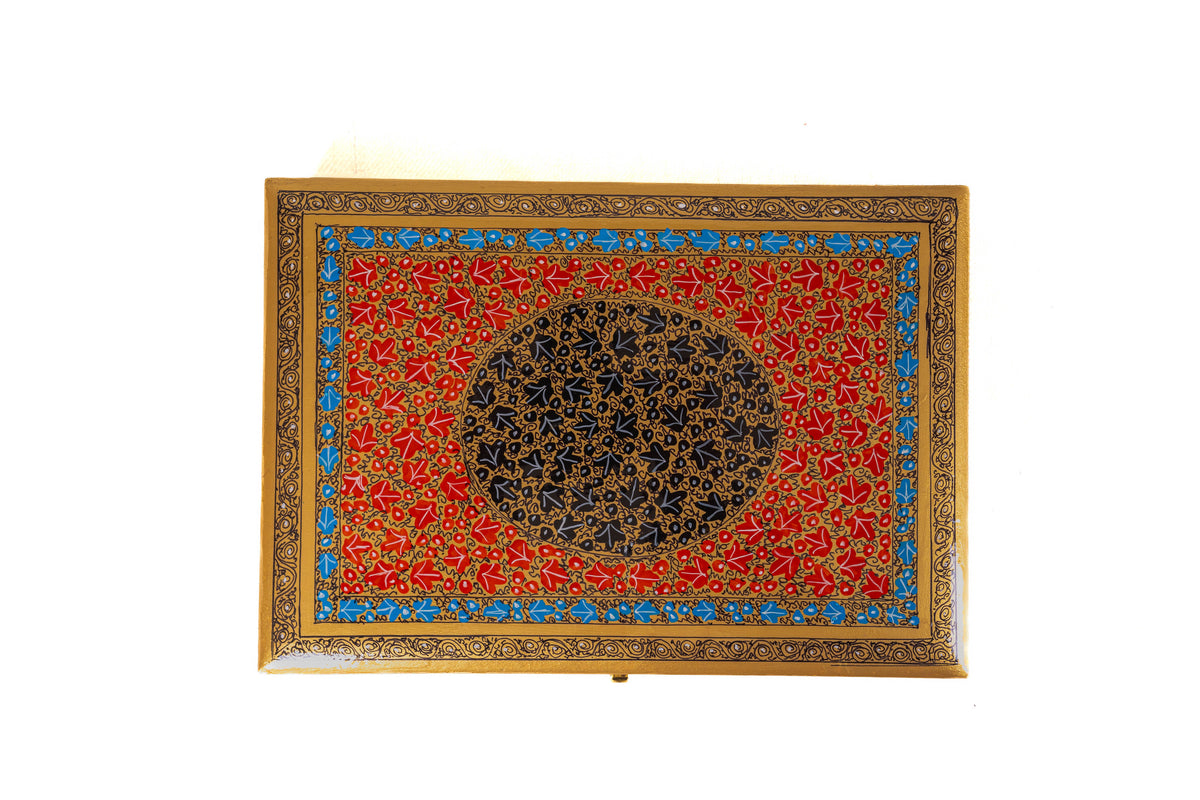 Top view of the red storage box lid with a dark floral medallion, delicate gold vines and a bright blue inner border.