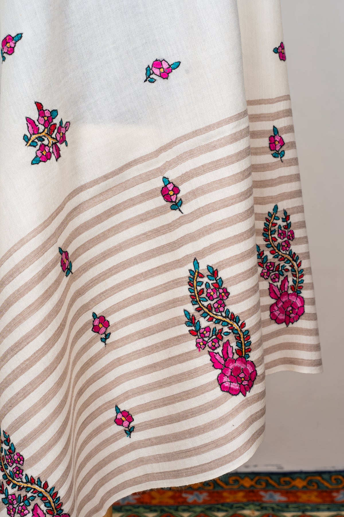 Detail of the shawl’s hanging folds showing beige striped panels, fuchsia flowers and teal-leaved paisley motifs