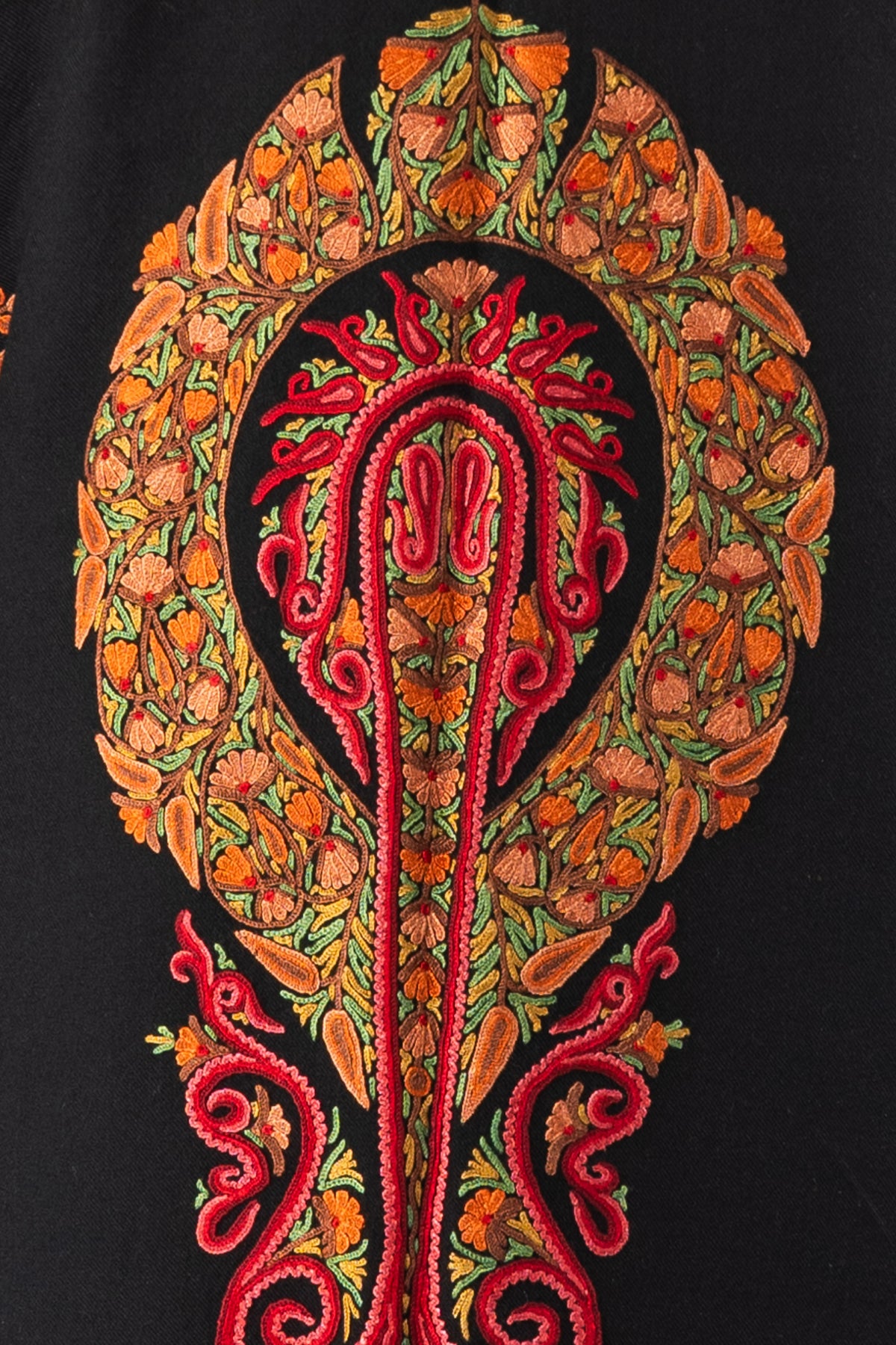 Close-up of an elongated red Aari scroll motif surrounded by orange flowers and green leaves on black jacket fabric