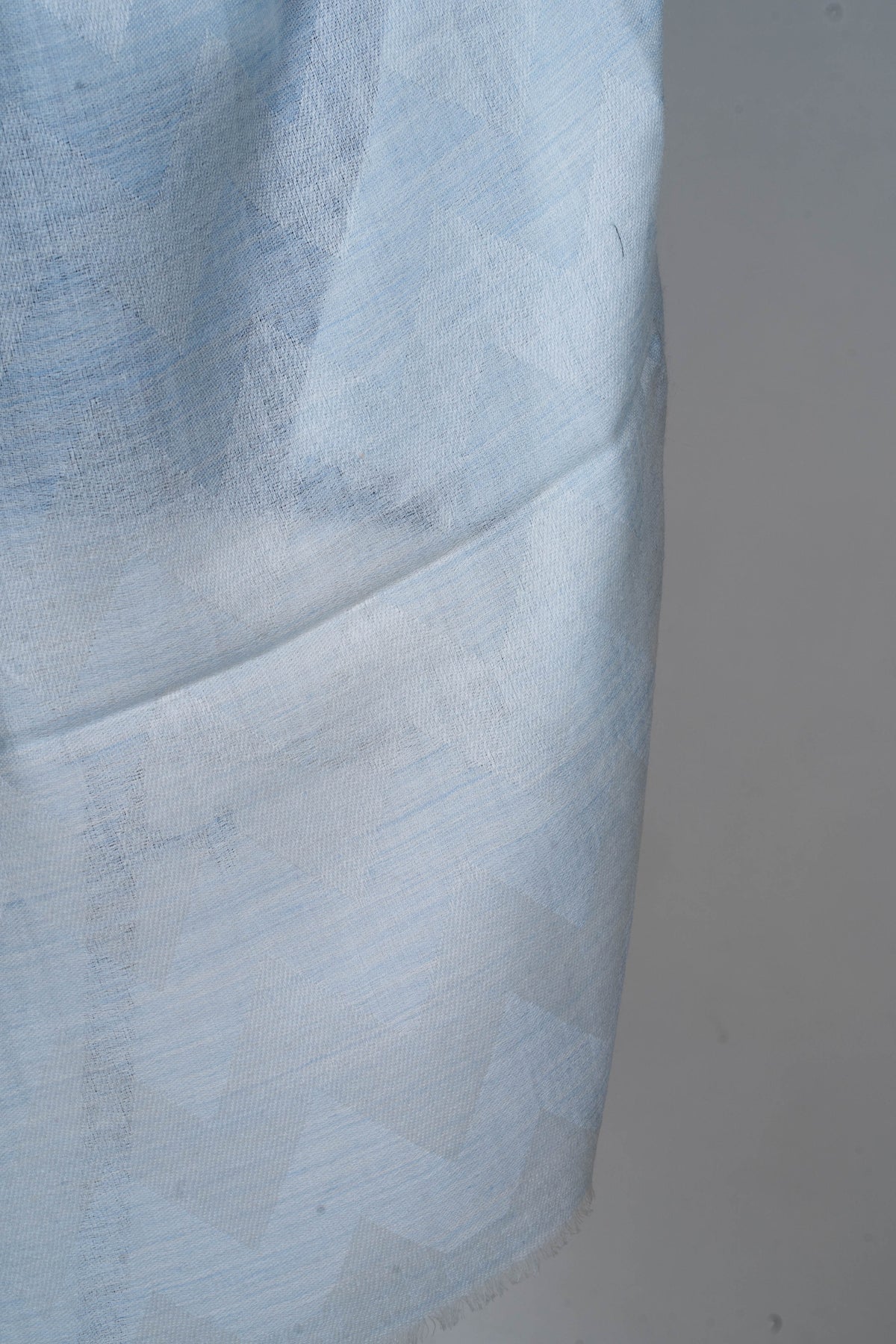 Fabric detail of the pale blue stole with a subtle tonal pattern and fine woven texture.