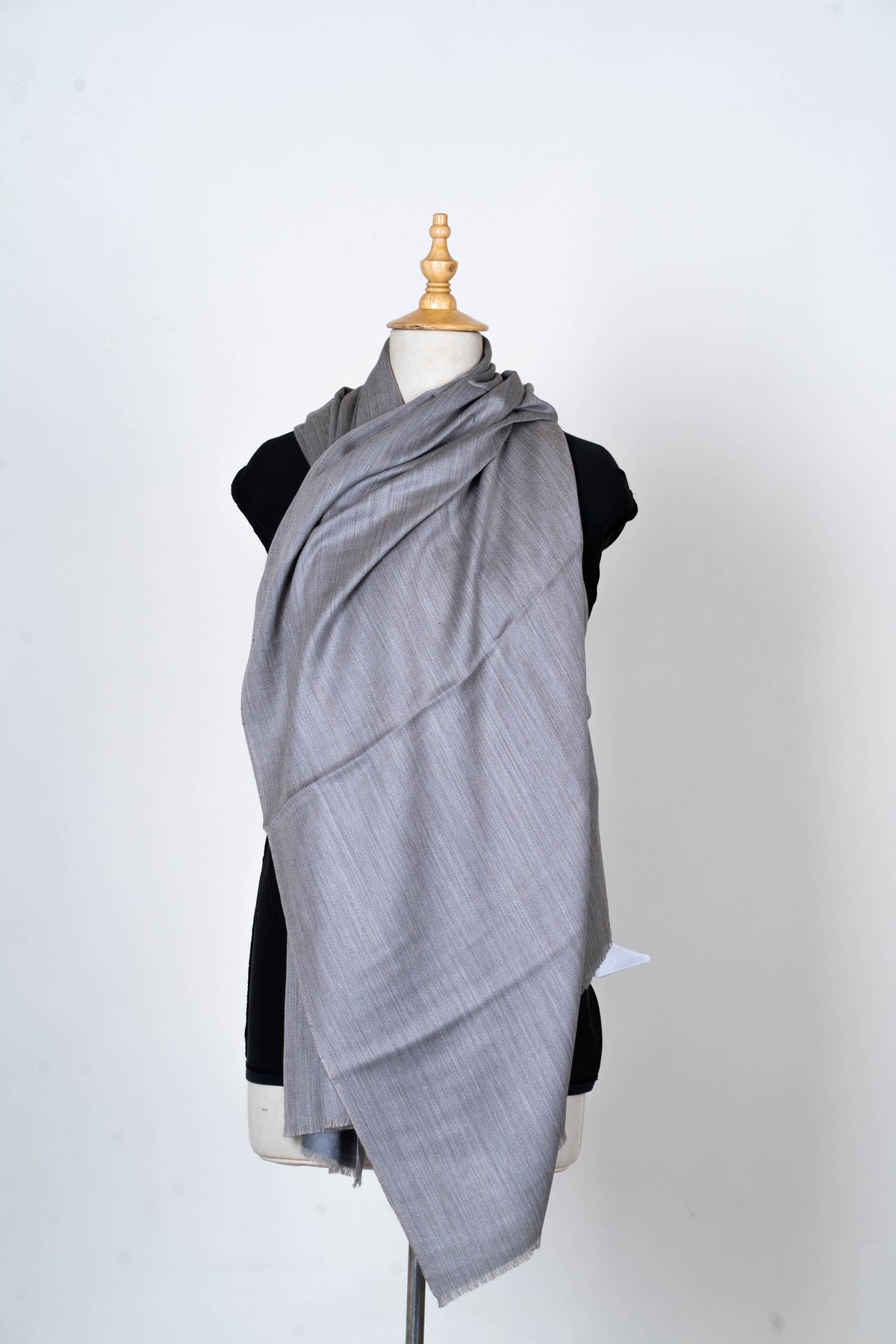 Grey side of a reversible Merino wool stole wrapped diagonally around a mannequin, with a pointed end hanging down