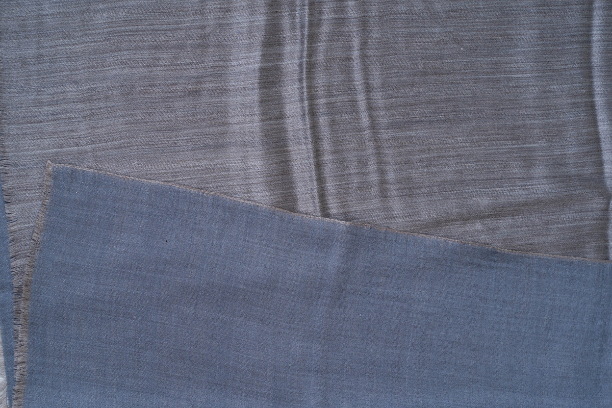 Folded reversible Merino wool stole showing its steel blue face over the contrasting slate grey side