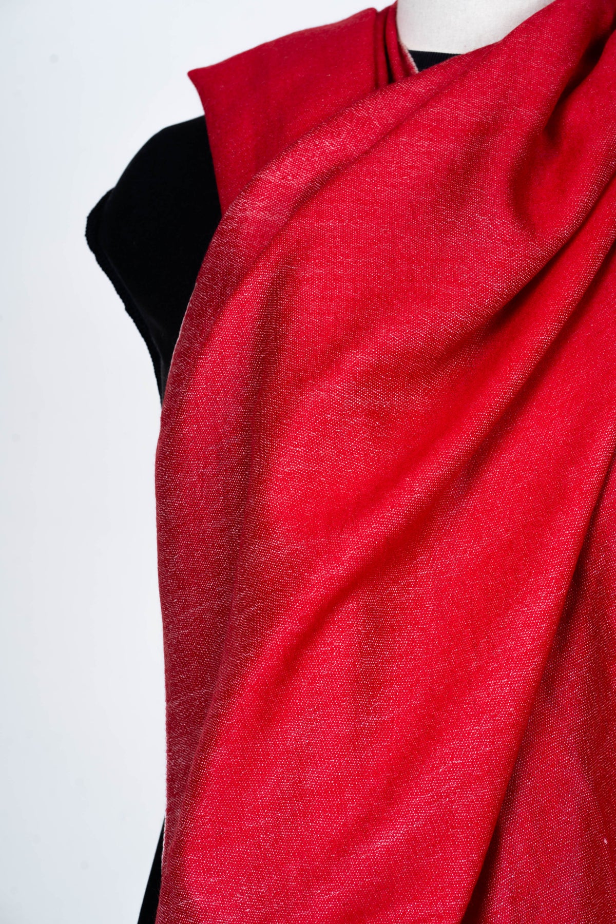 Close-up of the plain red stole across a mannequin chest, with soft folds and a fine textured weave.
