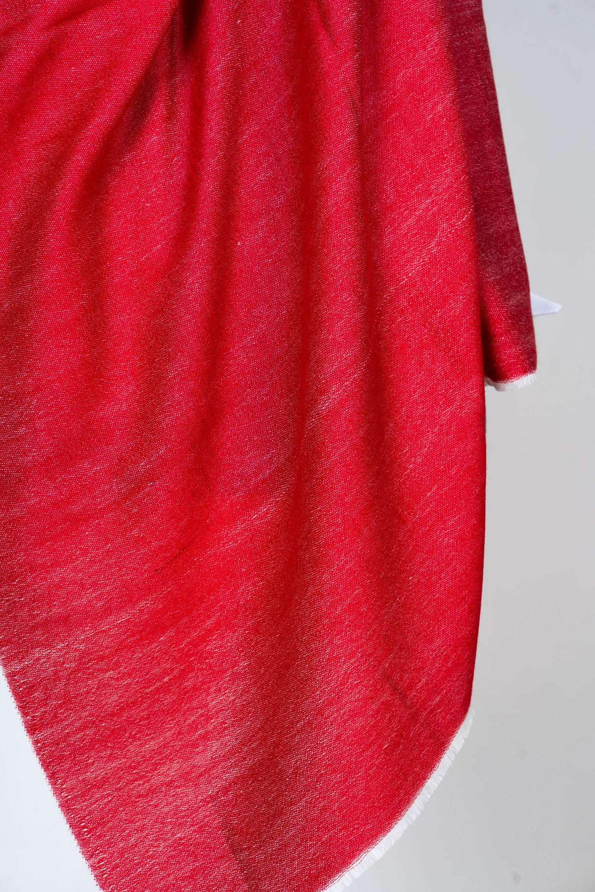 Detail of the hanging scarlet stole end, showing the woven texture and a thin pale edge.