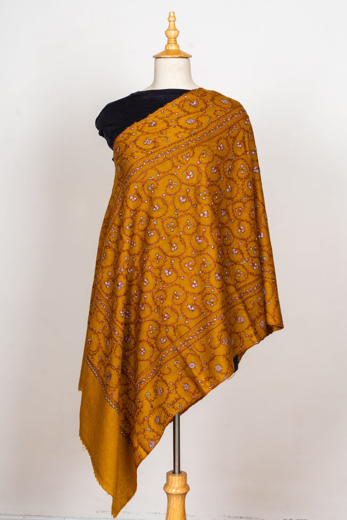 Full view of a mustard Merino wool stole on a mannequin, with fine Sozni floral vines and a plain end