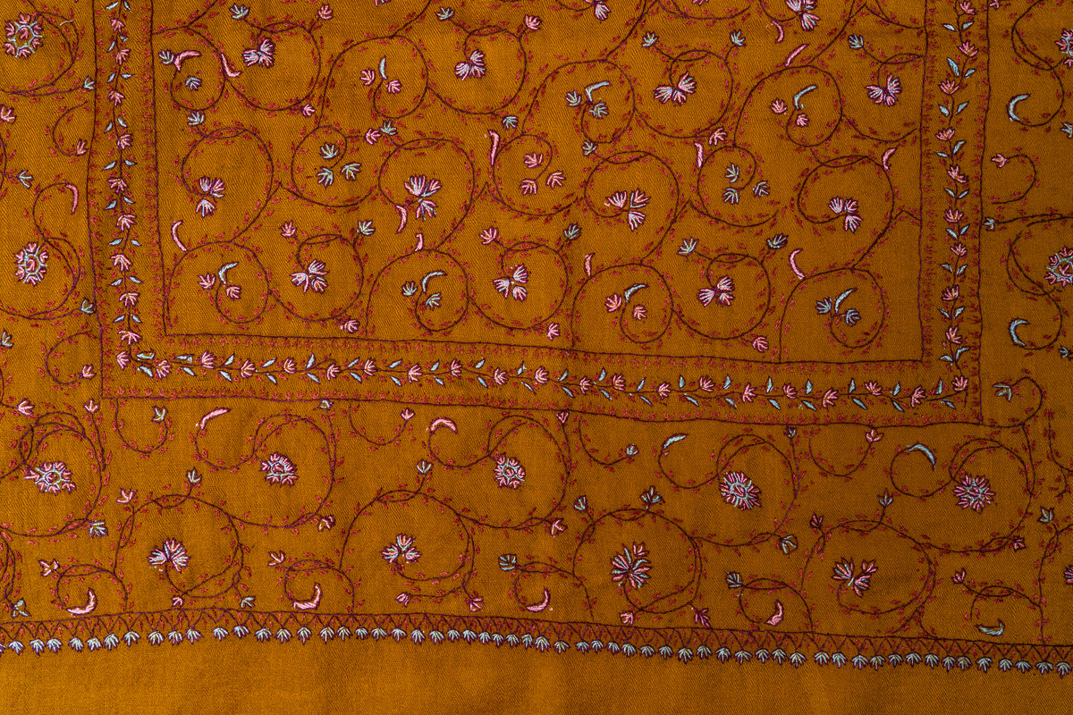 Close-up of small pink and white Sozni flowers on fine curling vines above the narrow border of a mustard stole