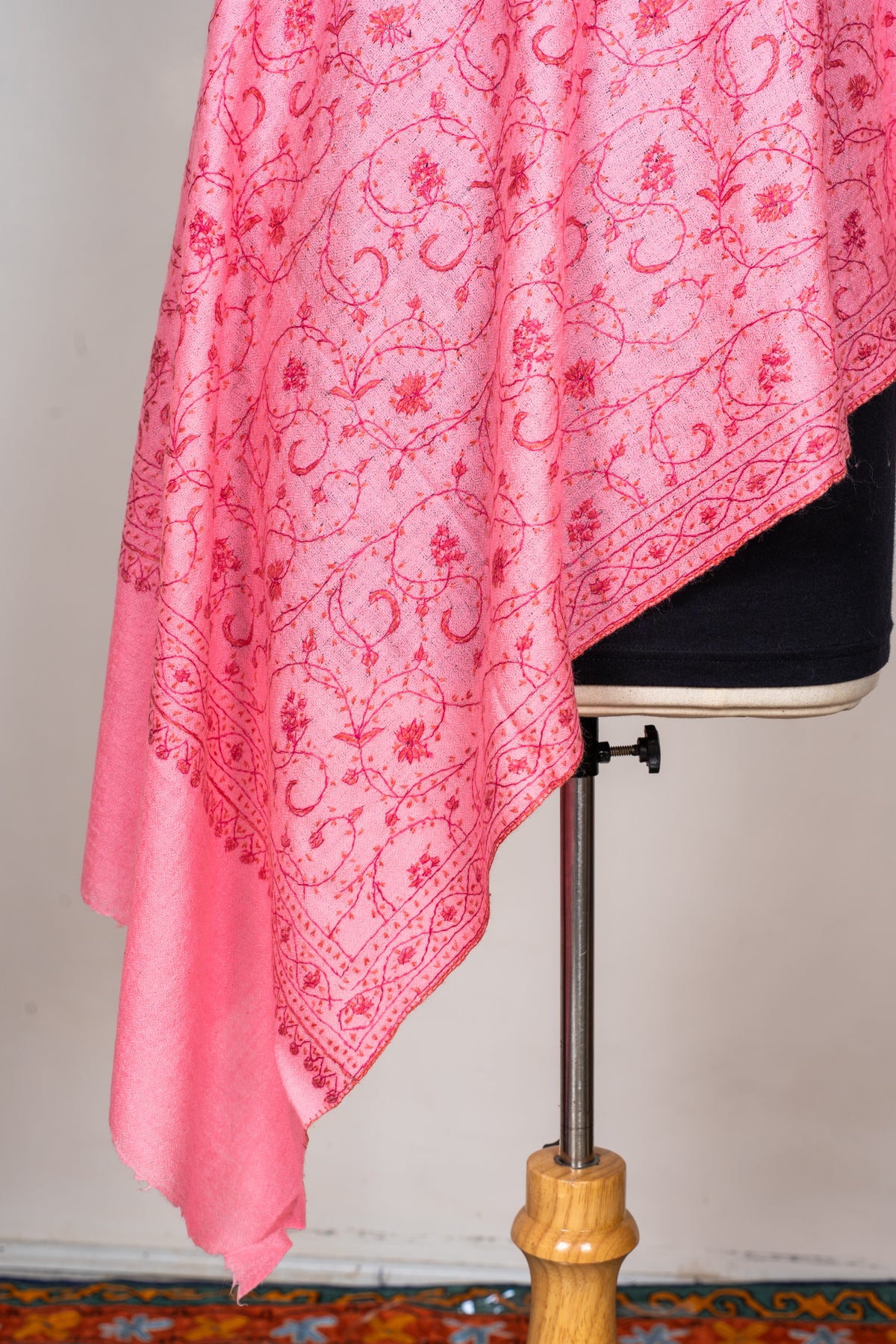 Detail of the stole’s hanging pink folds with scrolling floral embroidery, a patterned border and a plain end