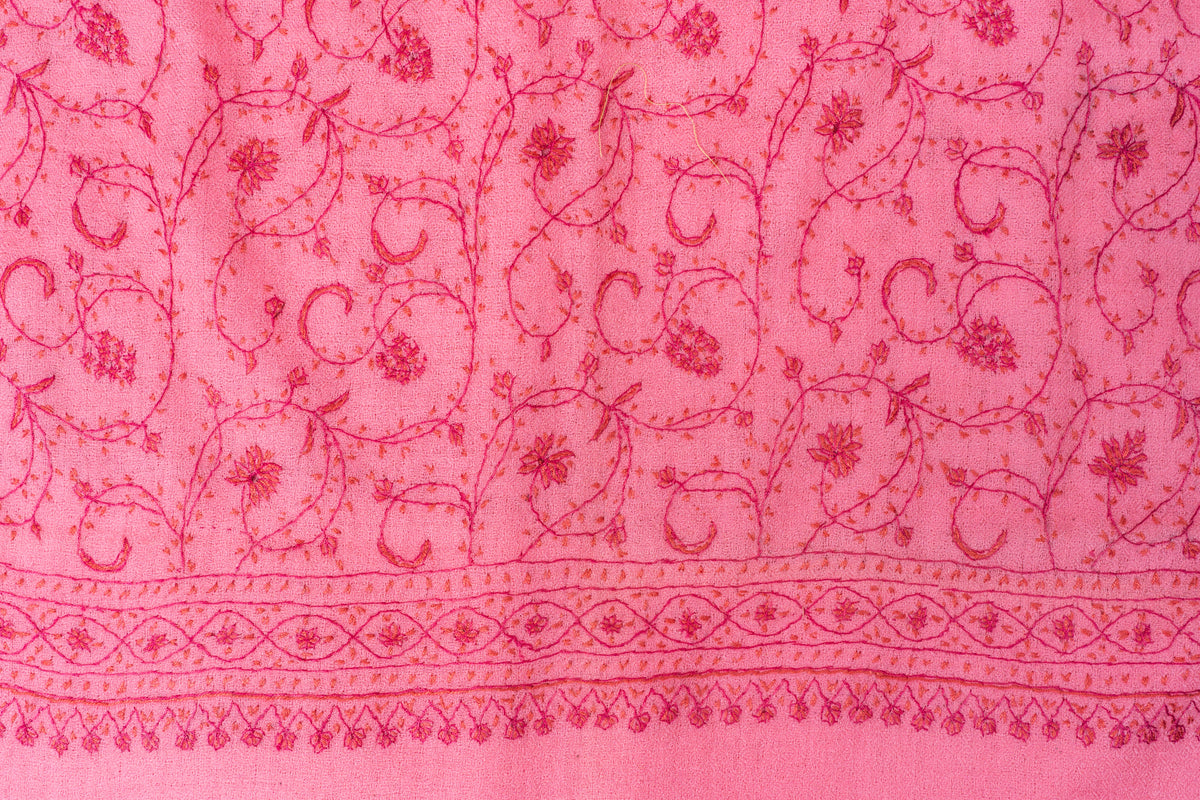Close-up of darker pink flowers, curling stems and a geometric floral border on the pink stole