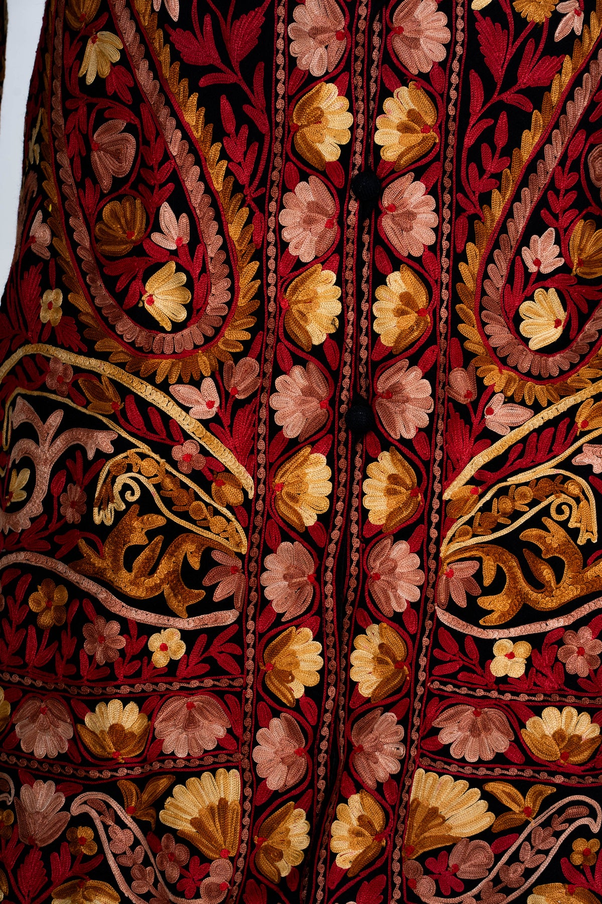 Lower front detail of the black jacket, with mirrored paisleys, flowers and curling embroidered bands around the fastening.
