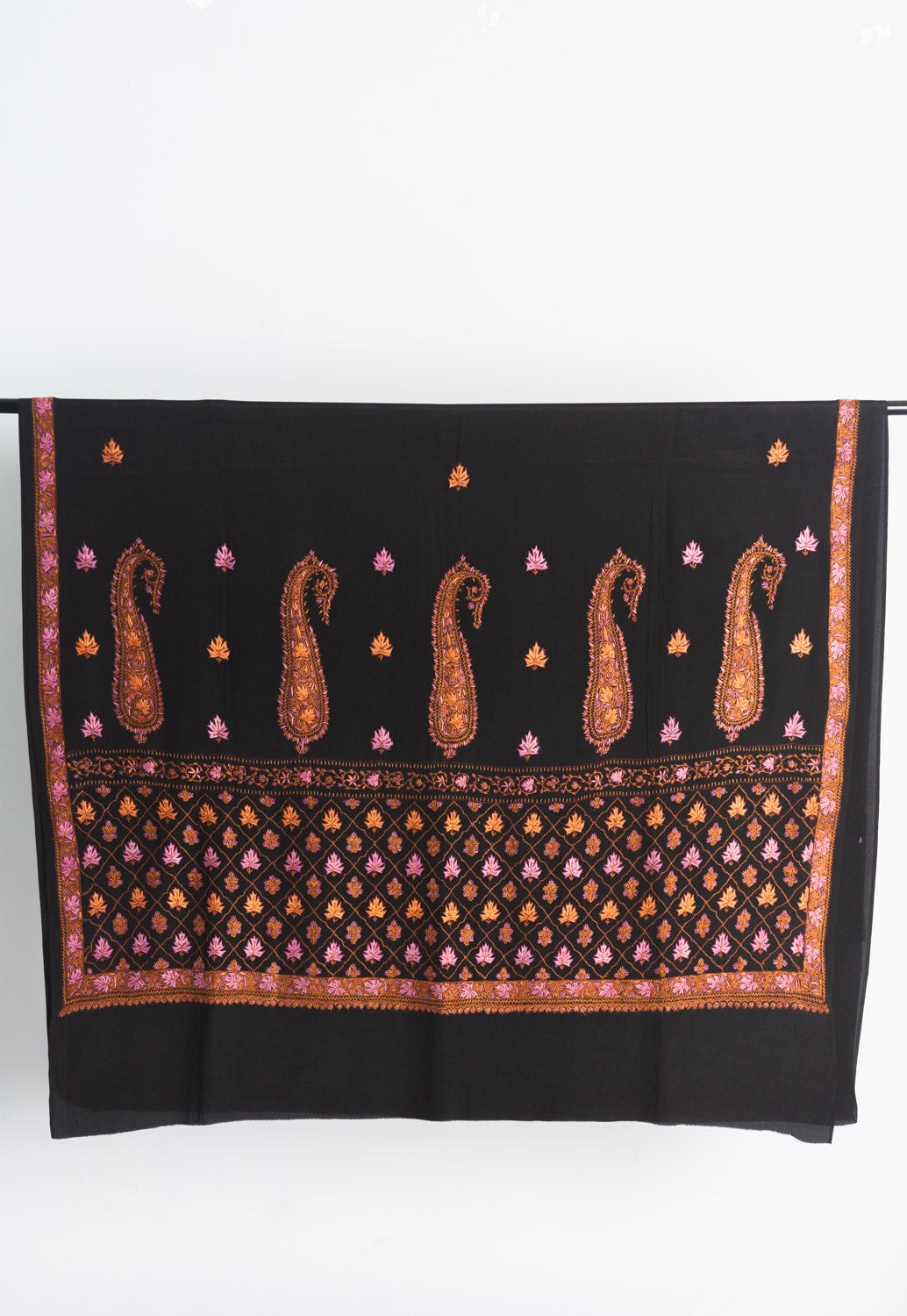 Black crepe saree end displayed flat, with five tall orange Sozni paisleys above a pink and orange diamond-patterned panel