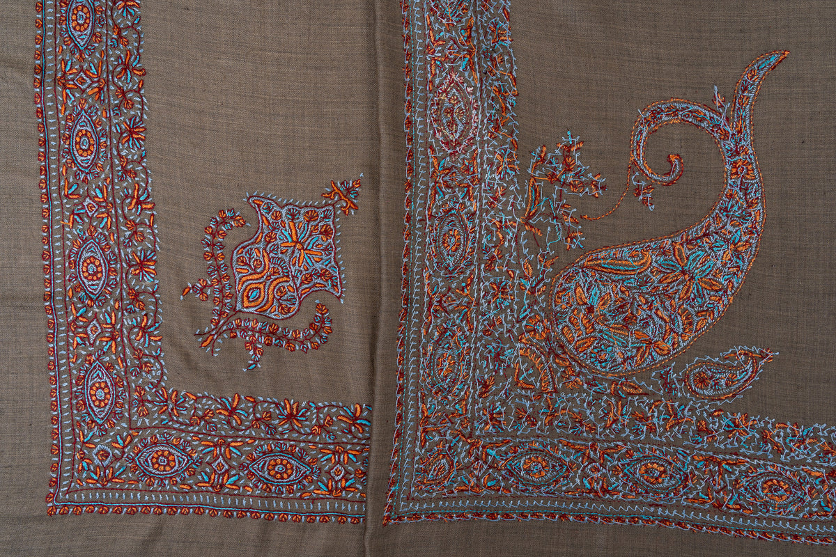 Overlapping cedar-brown rumal corners, showing both sides of turquoise and copper Sozni paisley and floral embroidery