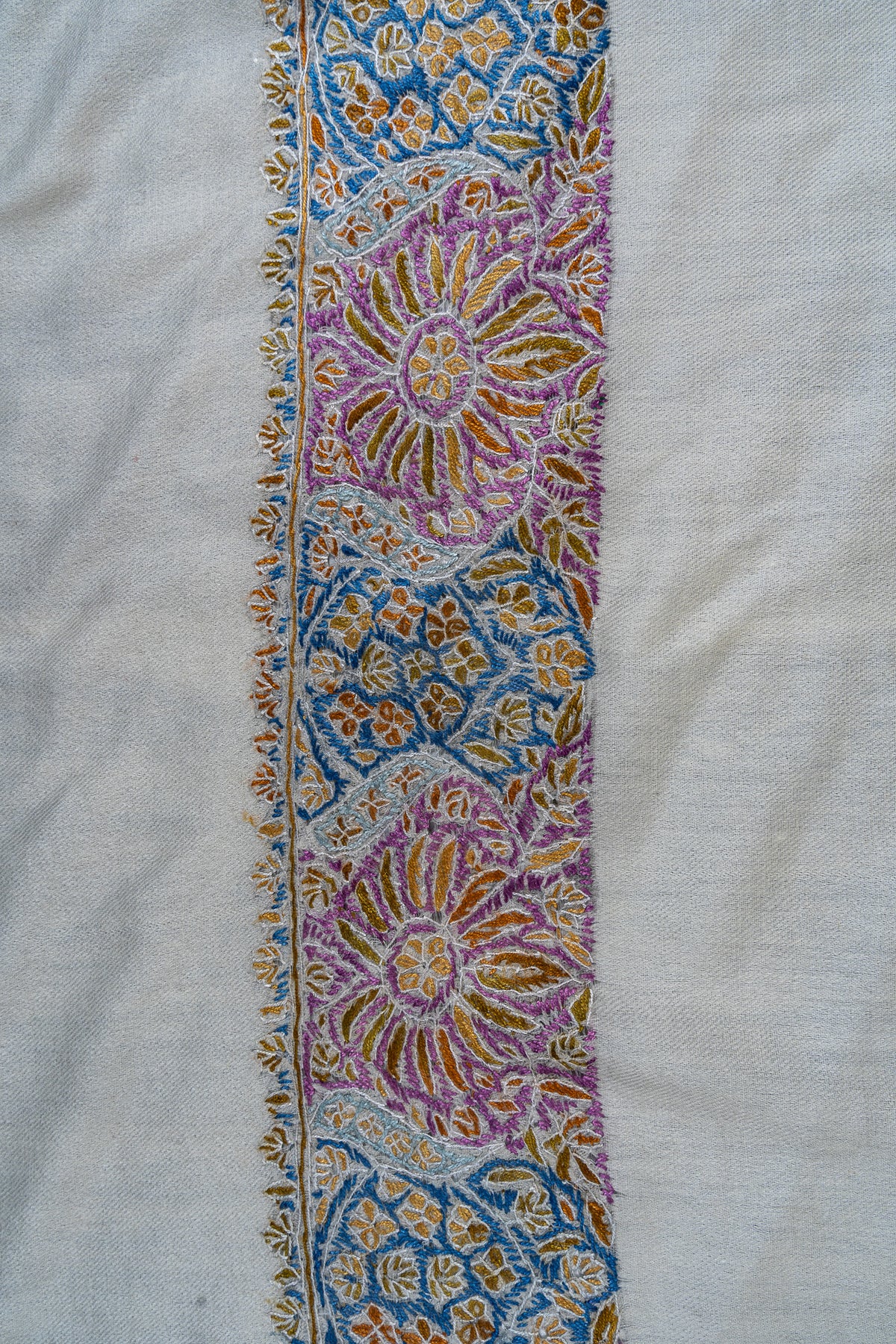 Wide Sozni border with alternating purple flowers and blue floral medallions, accented with gold stitching on ivory fabric