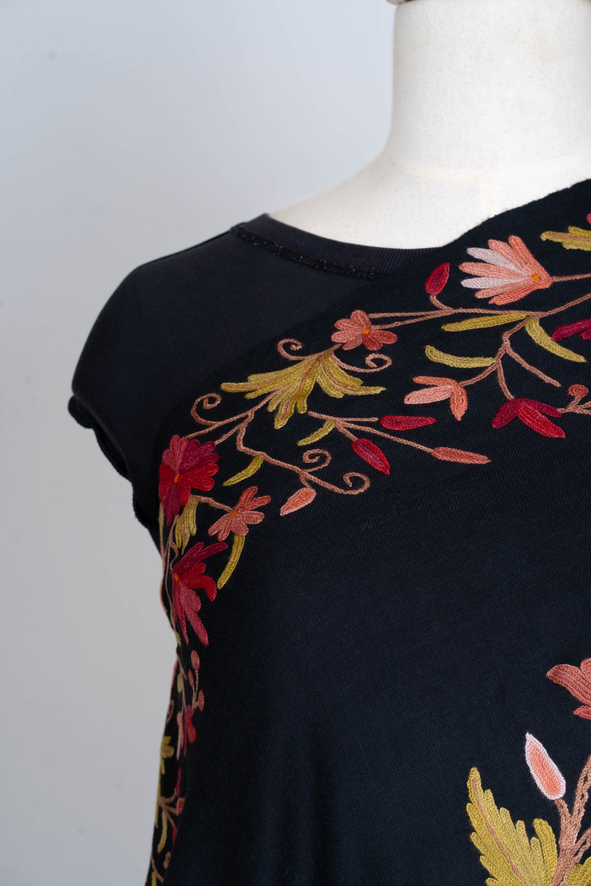 Shoulder detail of the black stole’s floral border with red and peach blossoms and gold-toned leaves.