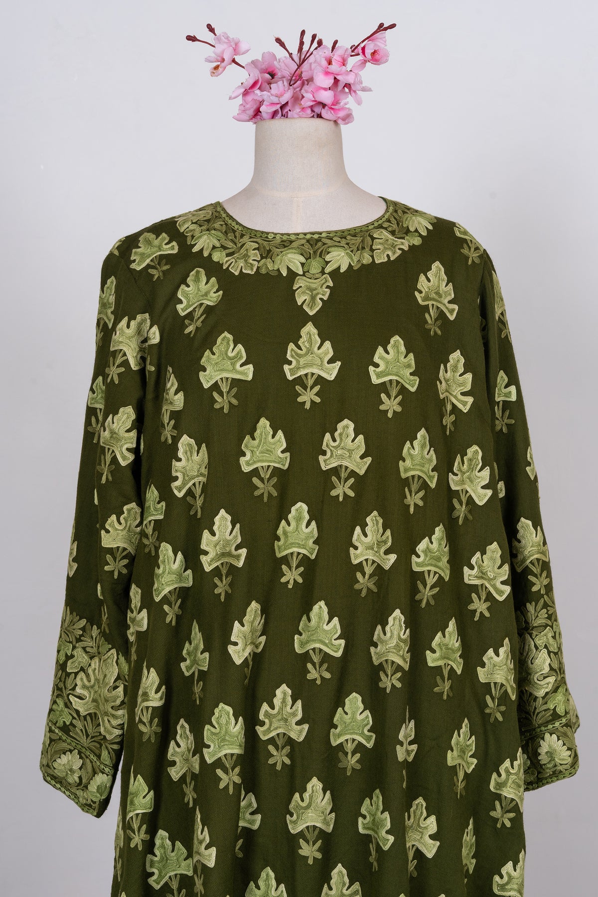 Upper front of the olive-green abaya with repeated pale leaf motifs, a leafy neckline and wide embroidered cuffs.