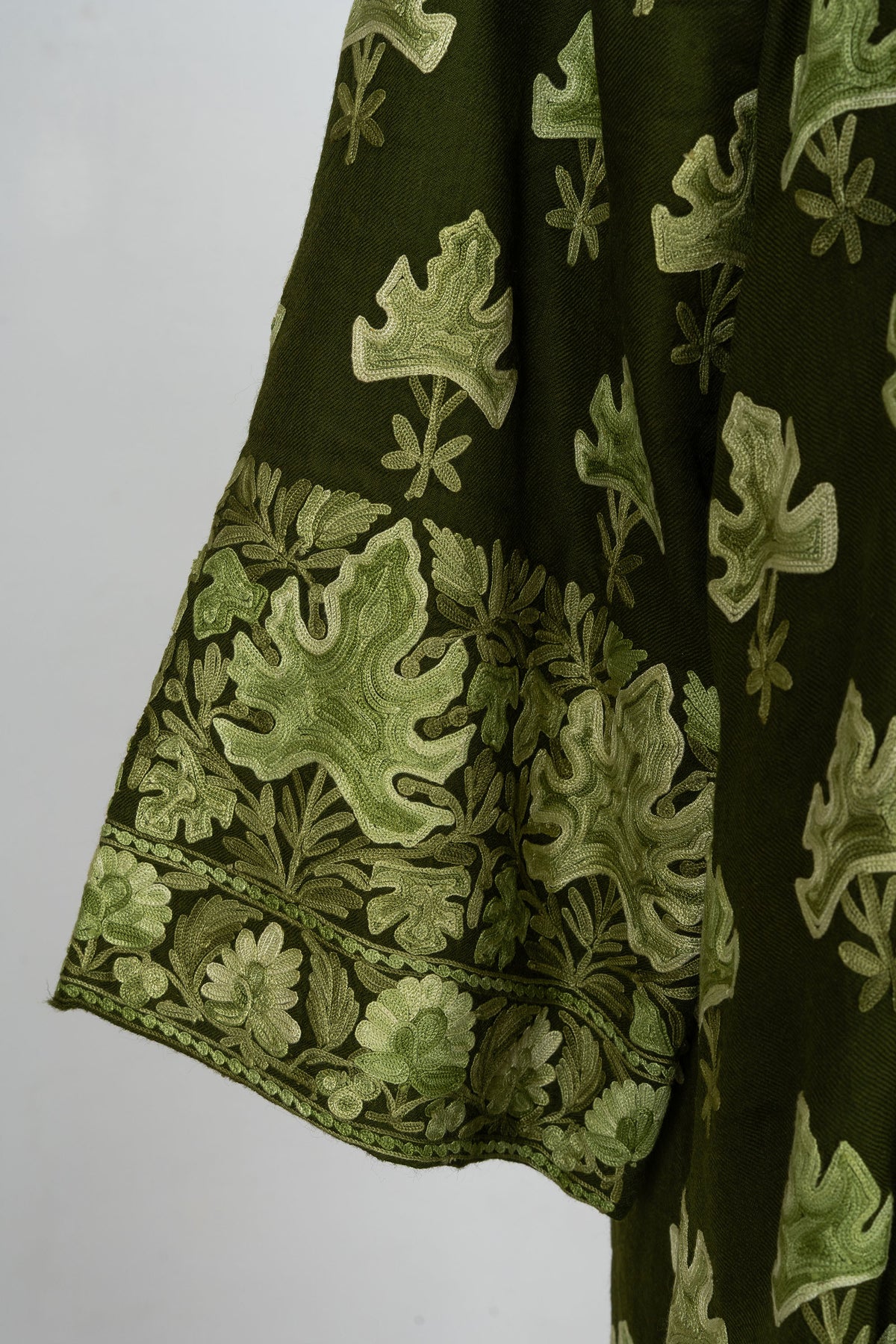 Close-up of the wide sleeve cuff with overlapping pale green leaves above a narrow flower border.