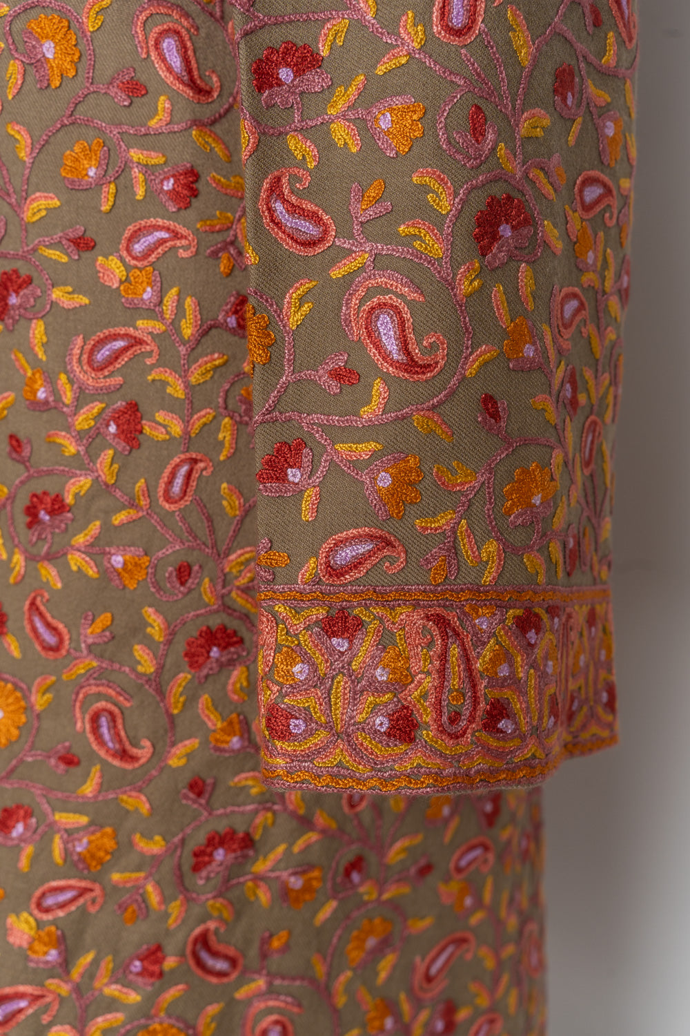 Brown jacket sleeve and cuff covered with pink paisleys, red flowers and orange leaves in Aari embroidery