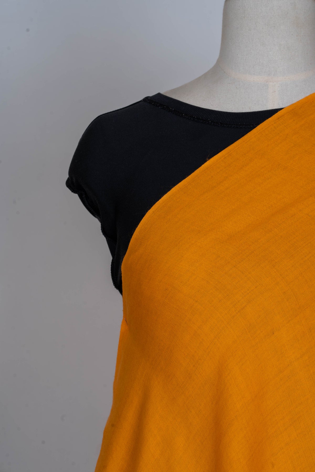Close-up of the golden-yellow wrap across a mannequin chest, showing its fine weave and unadorned edge.