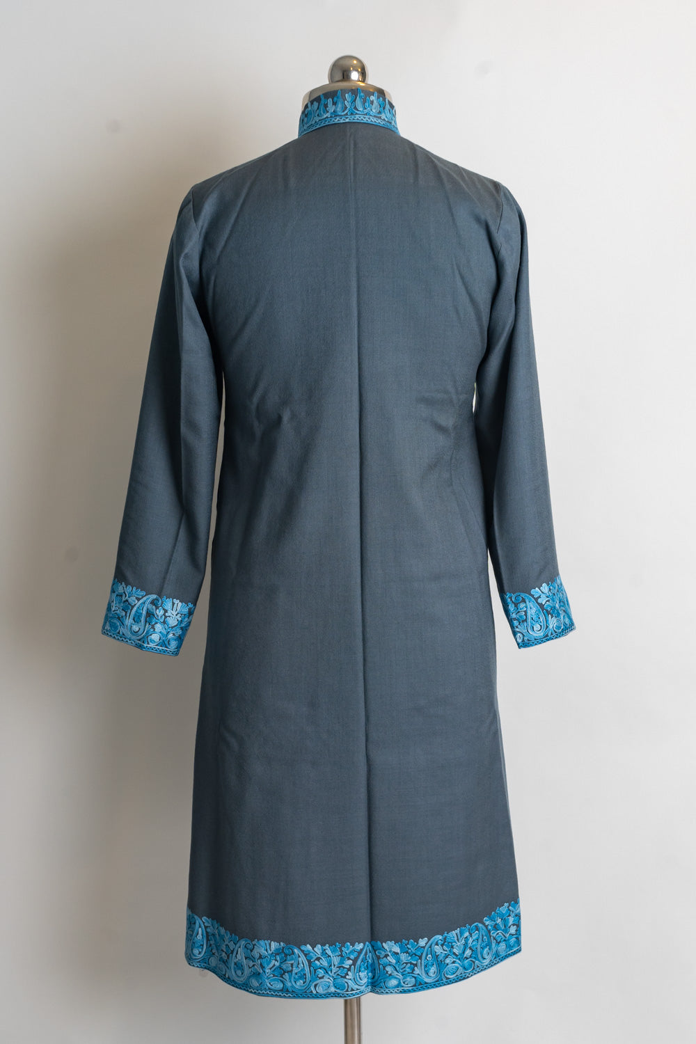 Back of a plain grey jacket with blue embroidered borders at the stand collar, cuffs and hem.