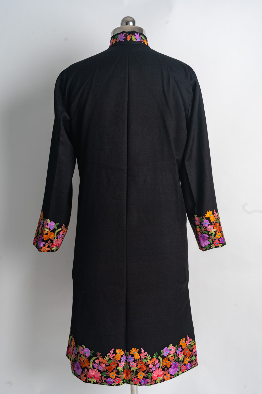 Back of the black jacket with a plain centre and colourful Aari floral embroidery at the collar, cuffs and hem.