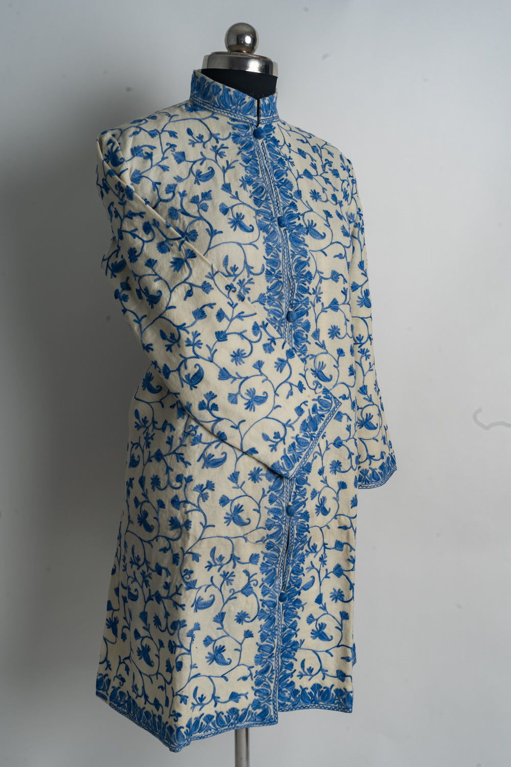 Angled full view of the cream-and-blue floral jacket with one sleeve across the body.