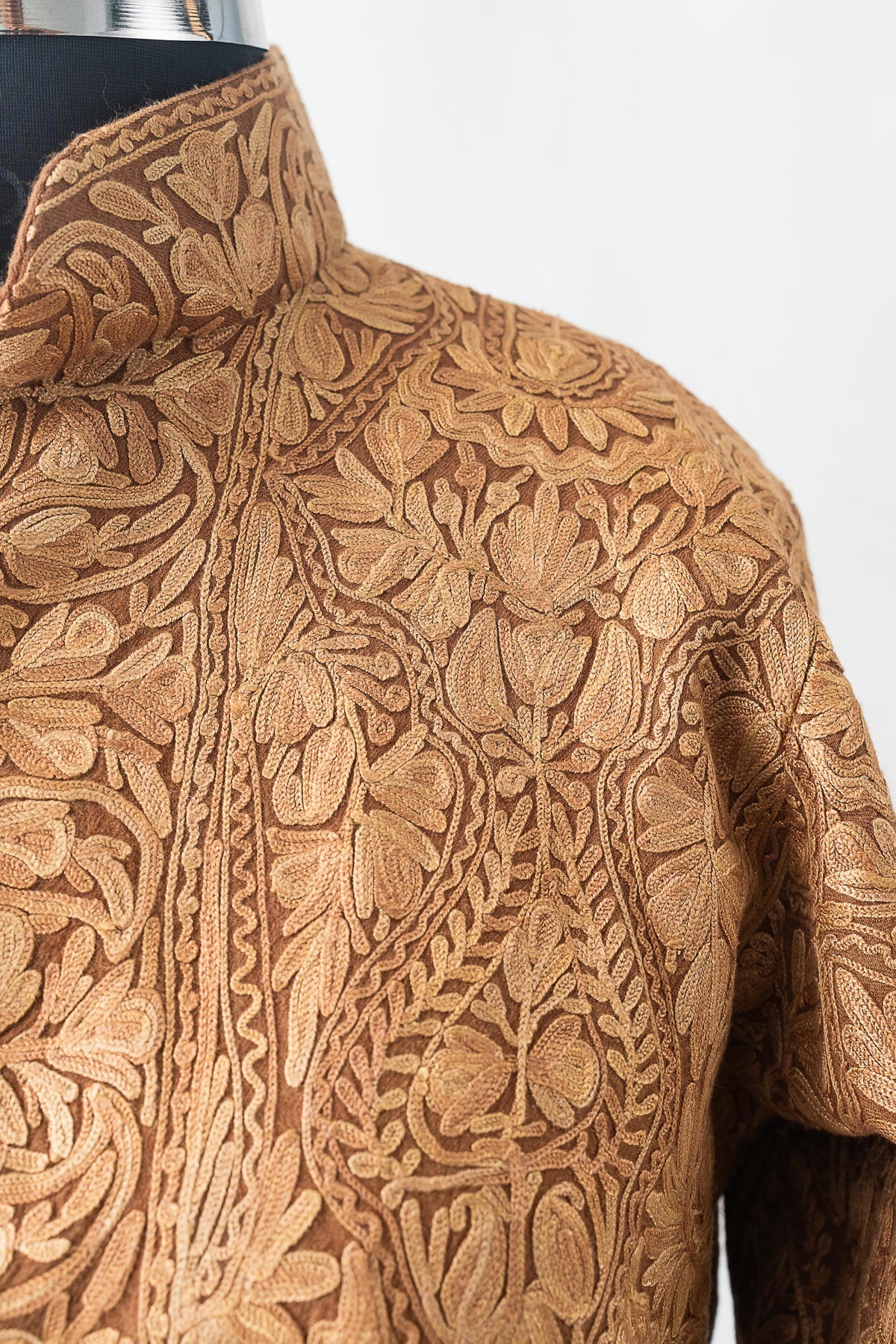 Shoulder and stand-collar detail of the beige jacket, densely embroidered with matching floral motifs