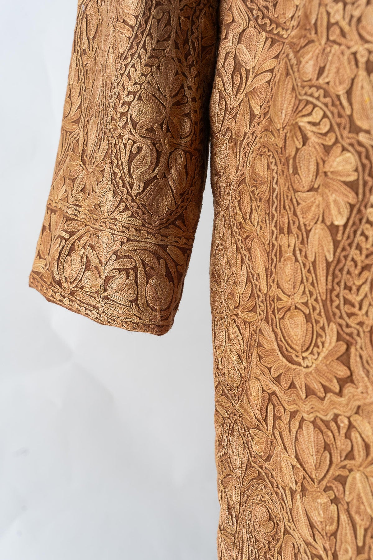 Lower sleeve and side detail of the beige jacket, showing tonal floral and paisley embroidery