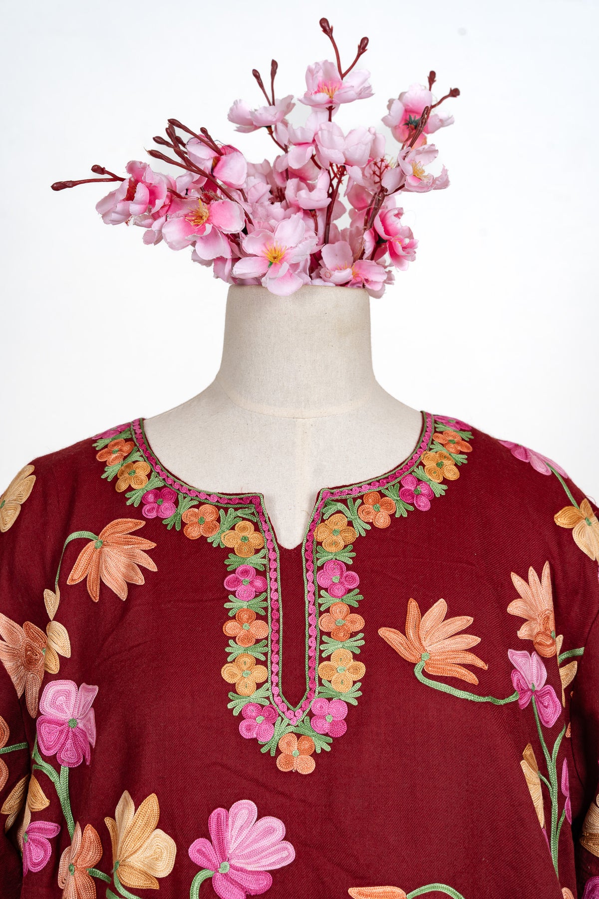 Close view of the crimson abaya’s rounded neckline and front slit, framed with small pink and orange flowers