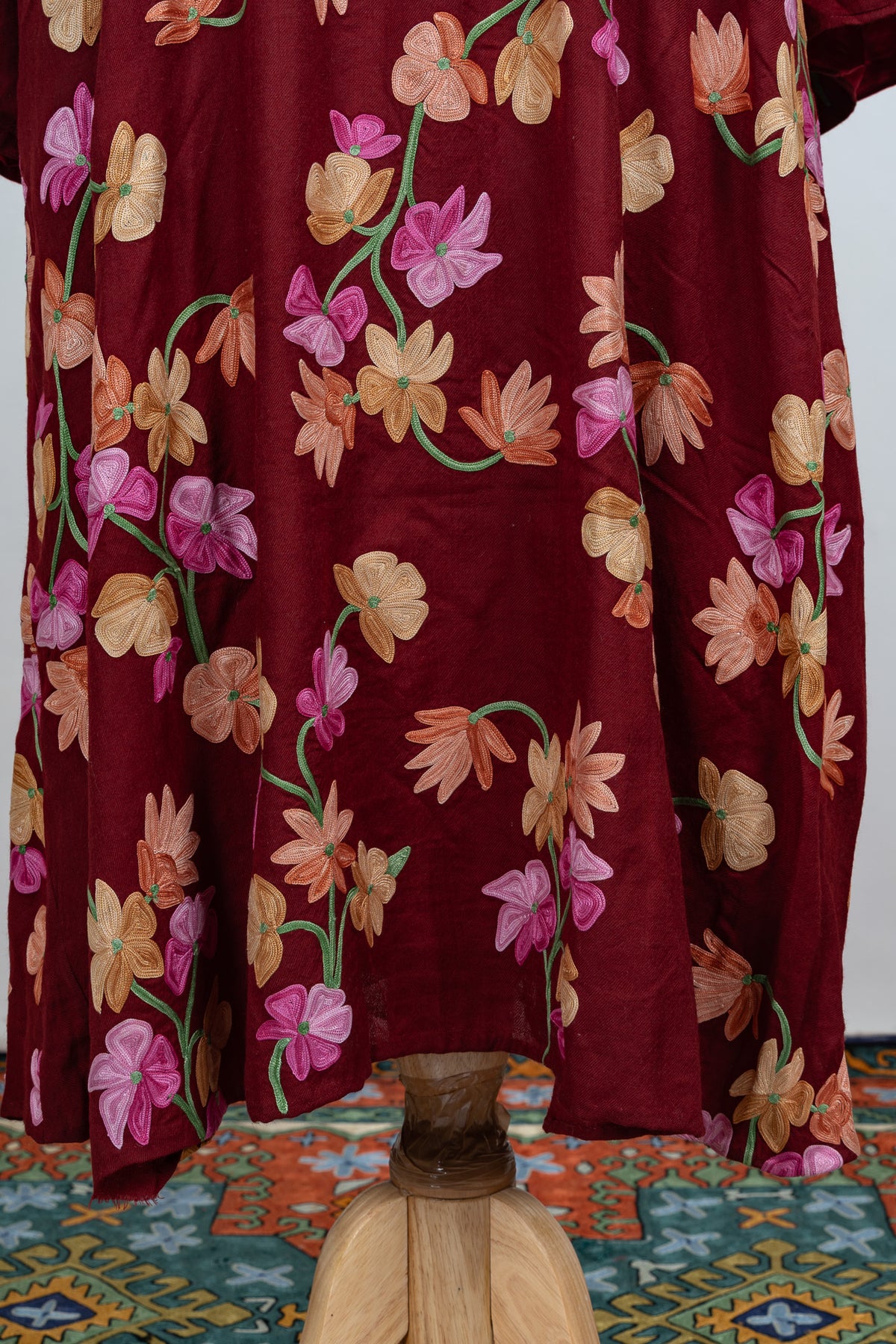 Close view of the crimson abaya’s lower skirt, with trailing pink and orange floral embroidery