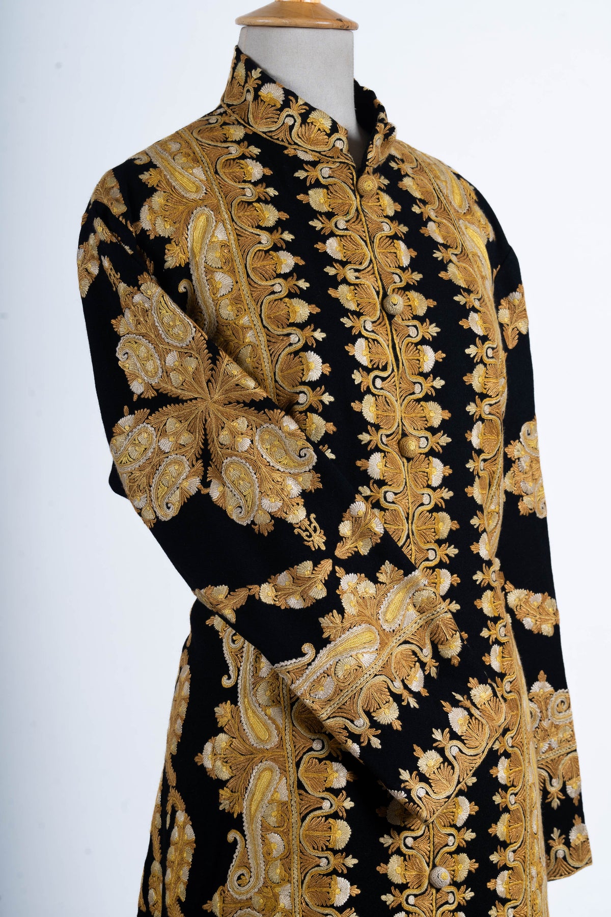 Angled upper-front view of the black jacket, showing gold-toned paisley and floral embroidery on the folded sleeve and front.
