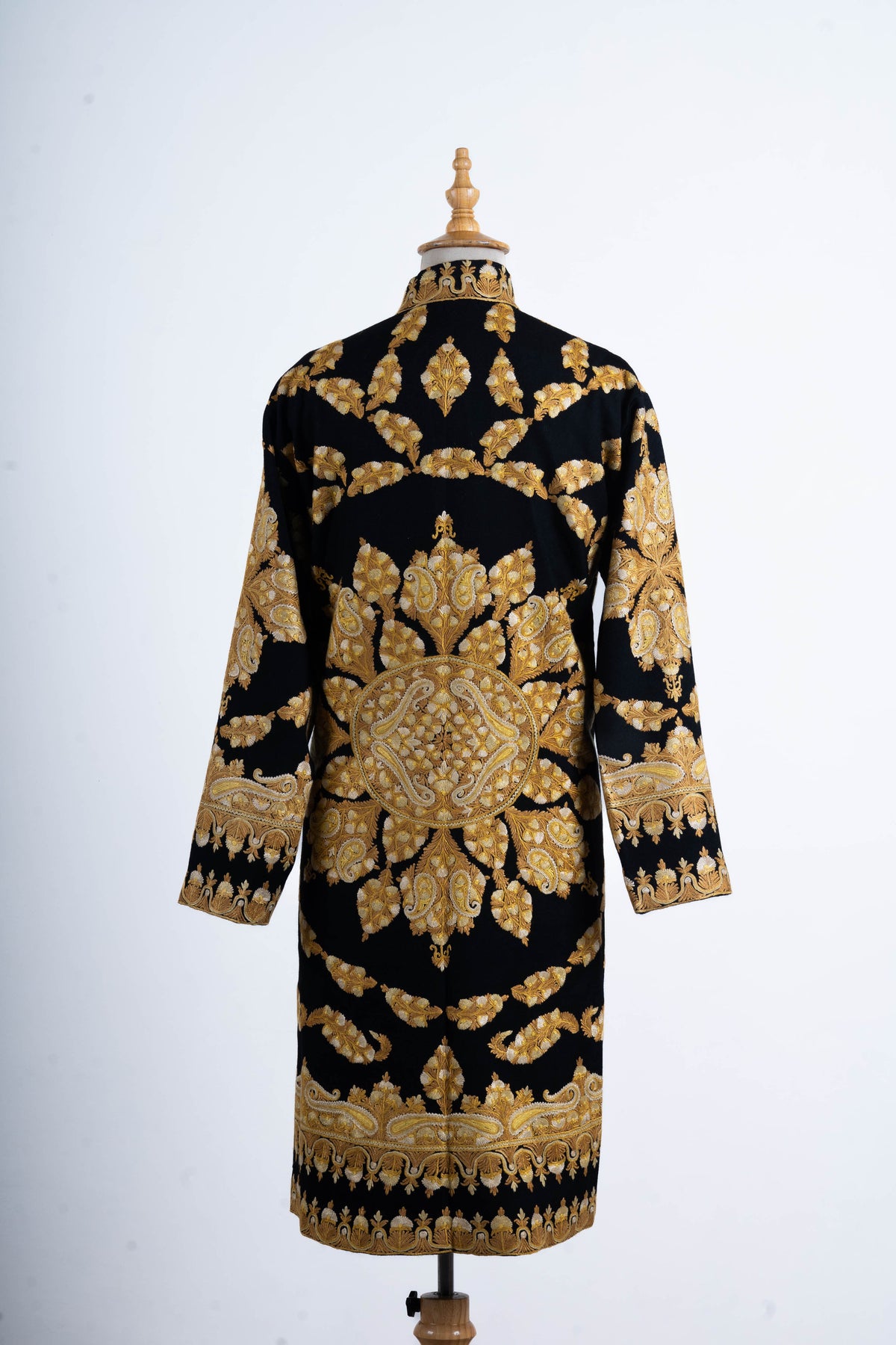 Back of the black long jacket with a large gold-toned floral medallion, curved vine bands and broad cuff and hem borders.