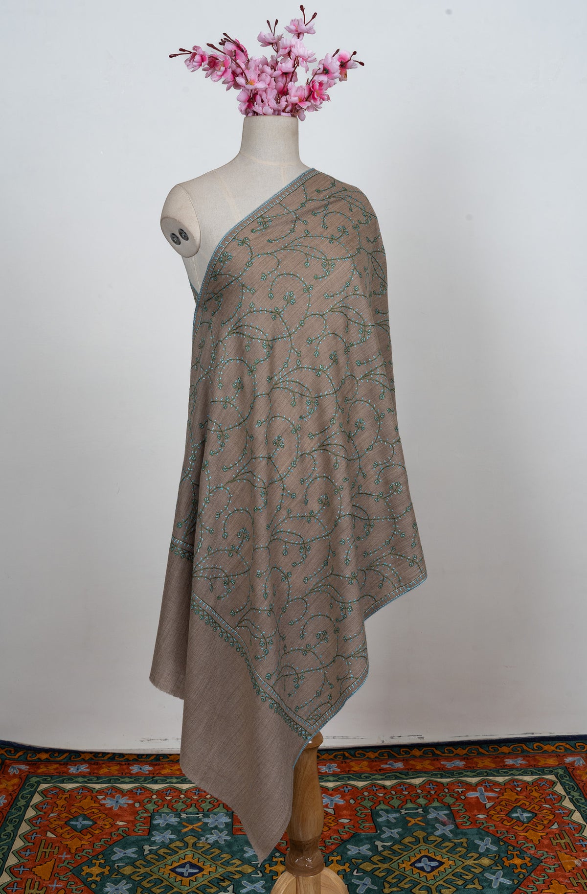 Full-length taupe Merino wool stole on a mannequin with teal Sozni vines across the body and plain end bands