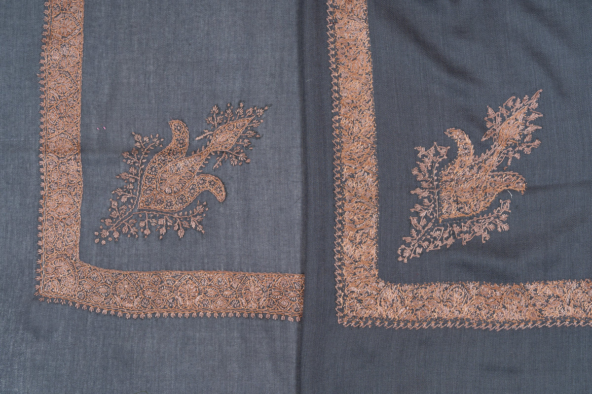 Overlapping slate-blue rumal corners, showing both sides of copper-toned Sozni floral motifs and borders