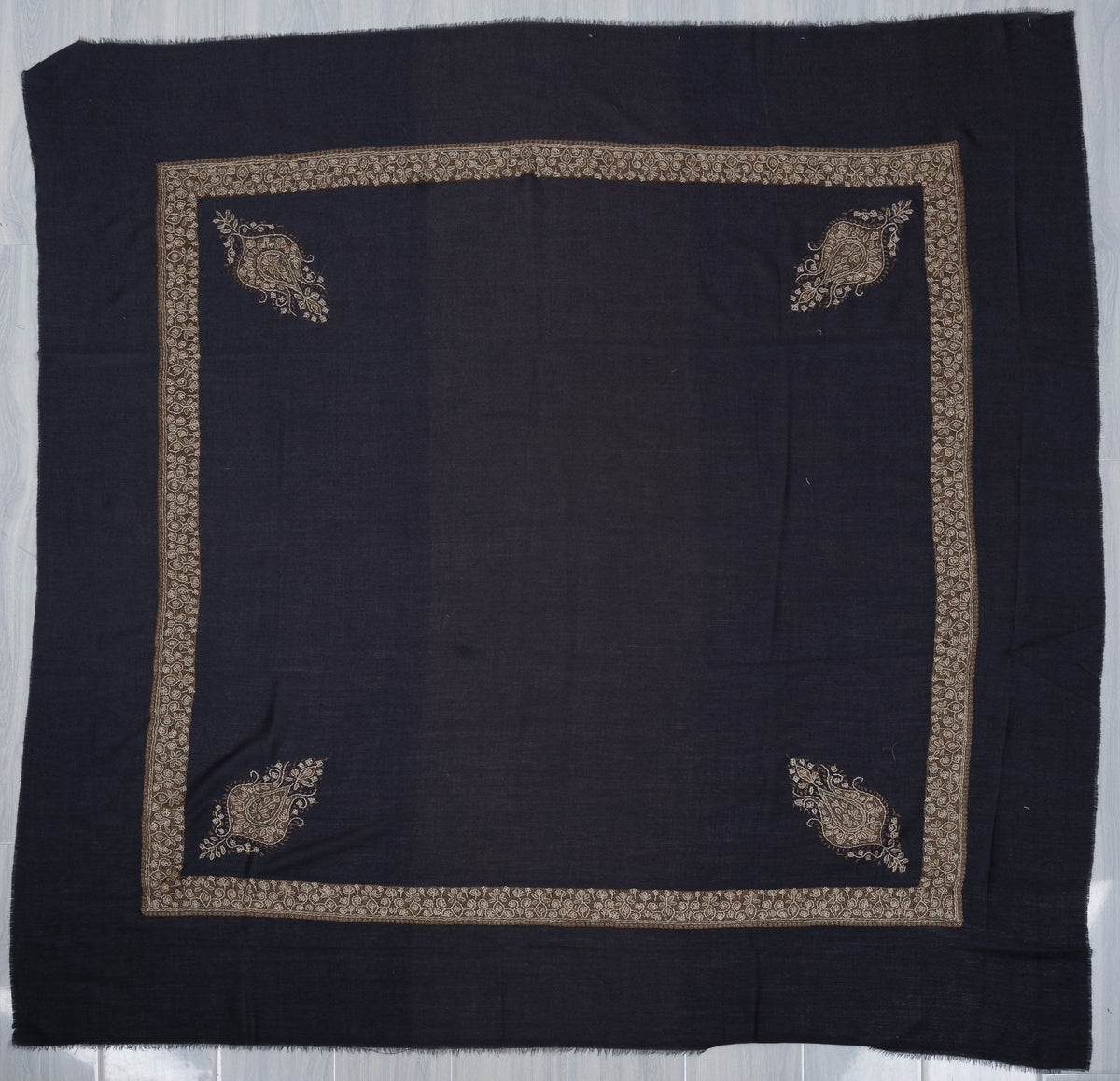 Navy merino wool rumal laid flat, with gold and ivory Sozni borders and four paisley corner motifs around a plain centre