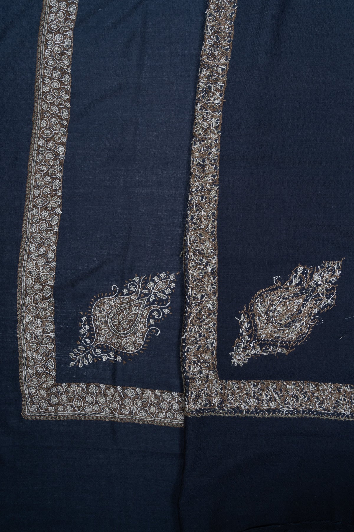Overlapping navy rumal corners showing gold and ivory Sozni floral borders and paisley motifs