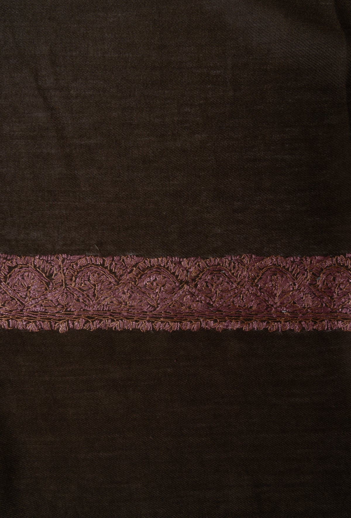 Close-up of a dusty rose Sozni border densely filled with floral and leaf stitching on cocoa-brown rumal fabric