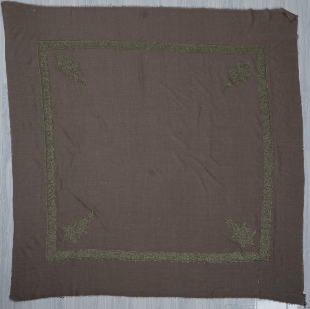 Smoky-brown square Merino wool rumal laid flat with olive-green Sozni borders, four corner motifs and a plain centre.