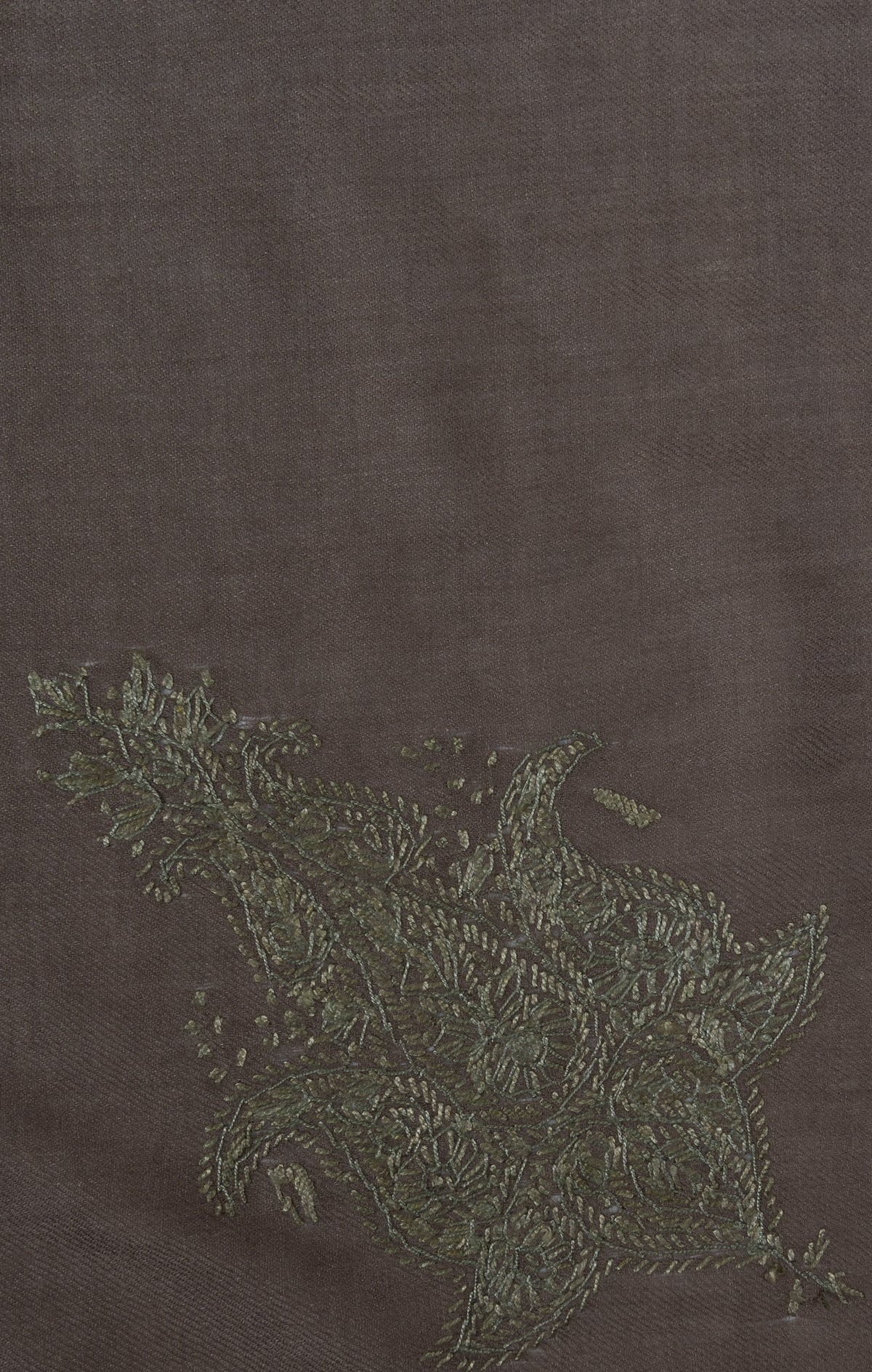 Close-up of an olive-green Sozni corner motif filled with fine flowers and leaves on smoky-brown Merino wool.