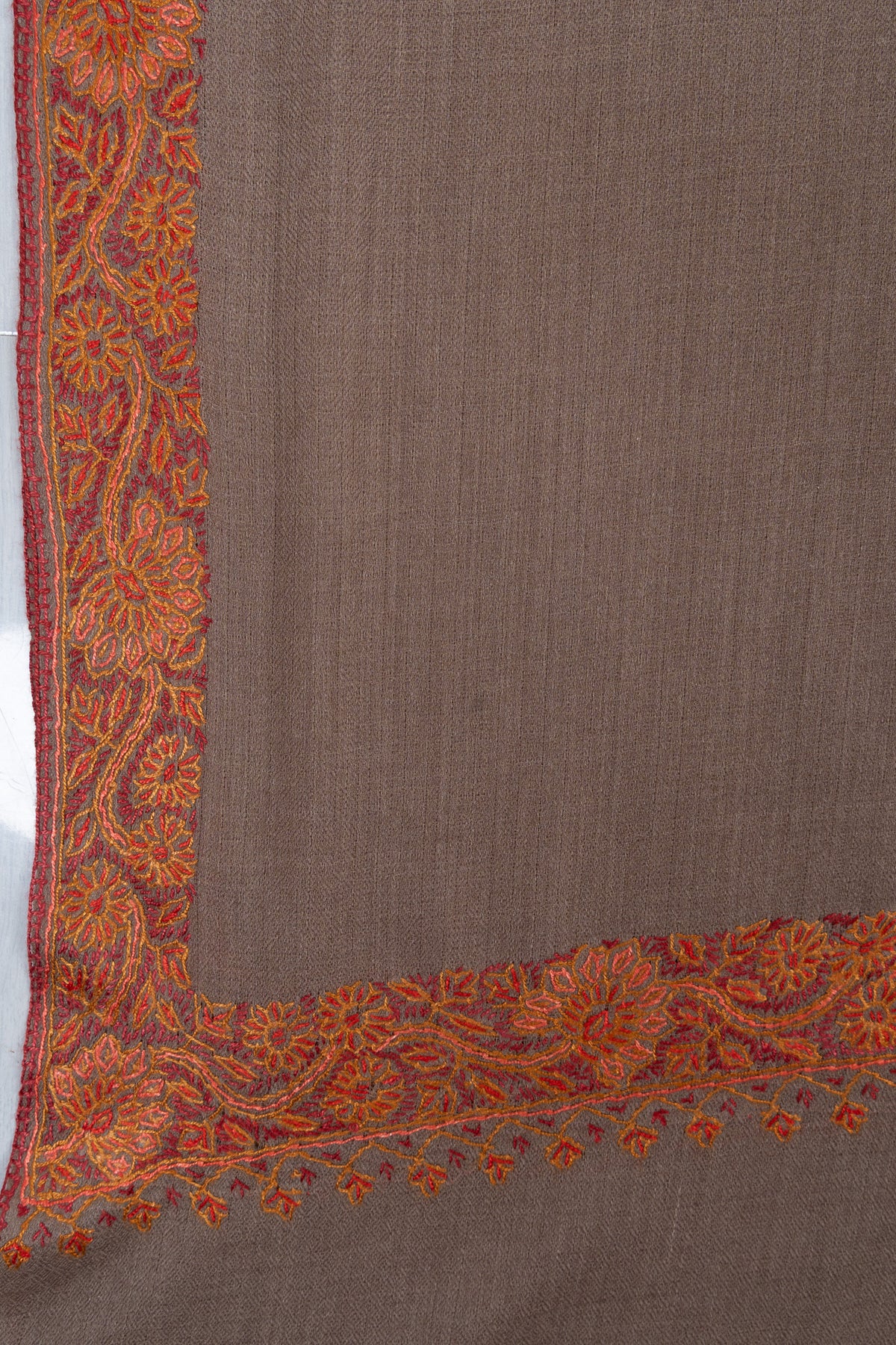 Truffle-brown shawl corner with rust-orange floral embroidery and small hanging flower motifs