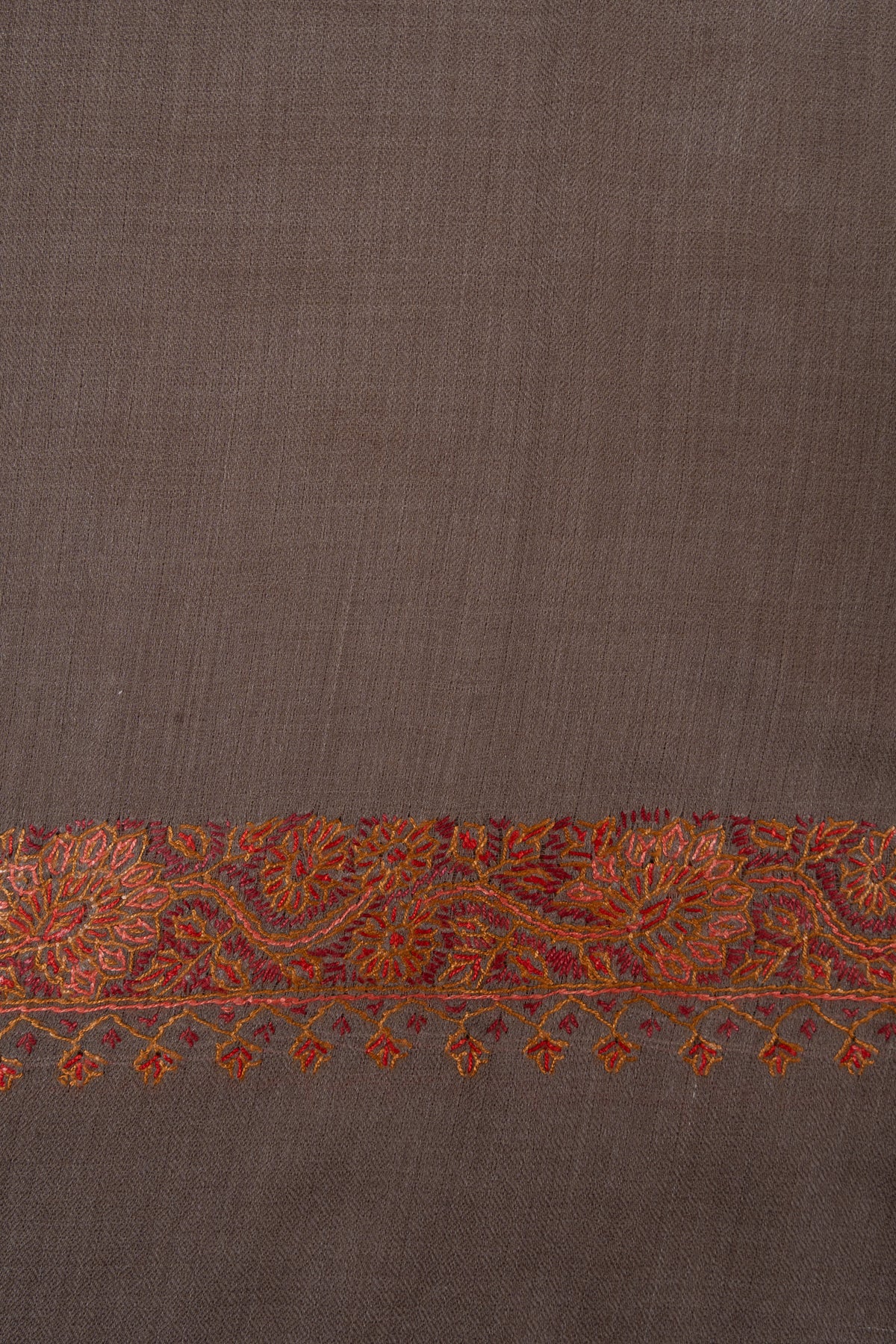 Close-up of rust-orange flowers and curling stems in the truffle-brown shawl's end border