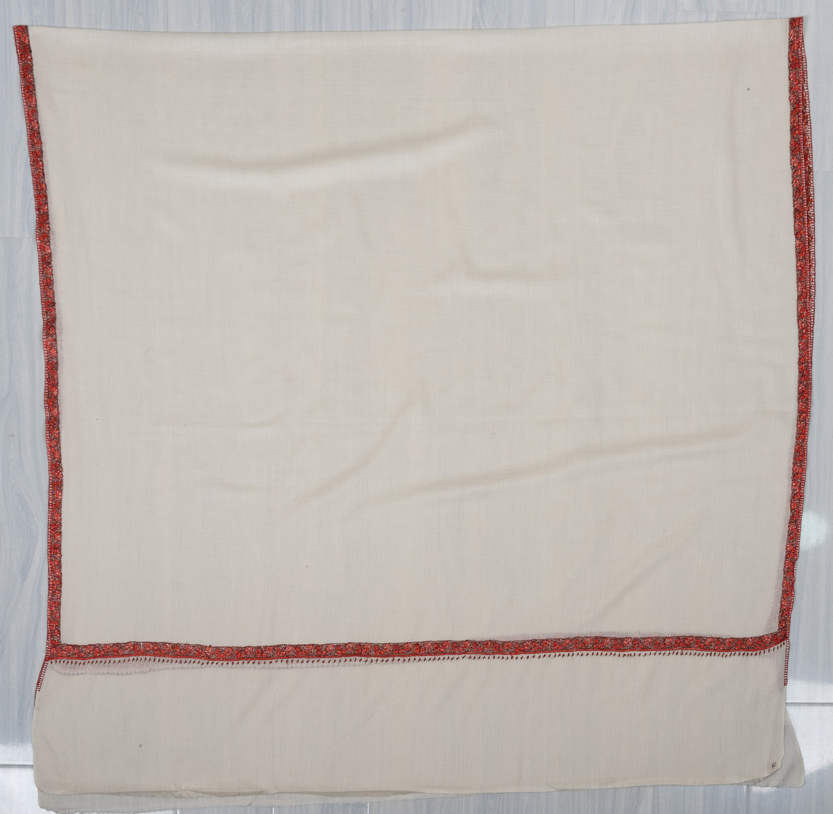 Ivory shawl laid flat with a plain centre framed by narrow ember-red Sozni borders