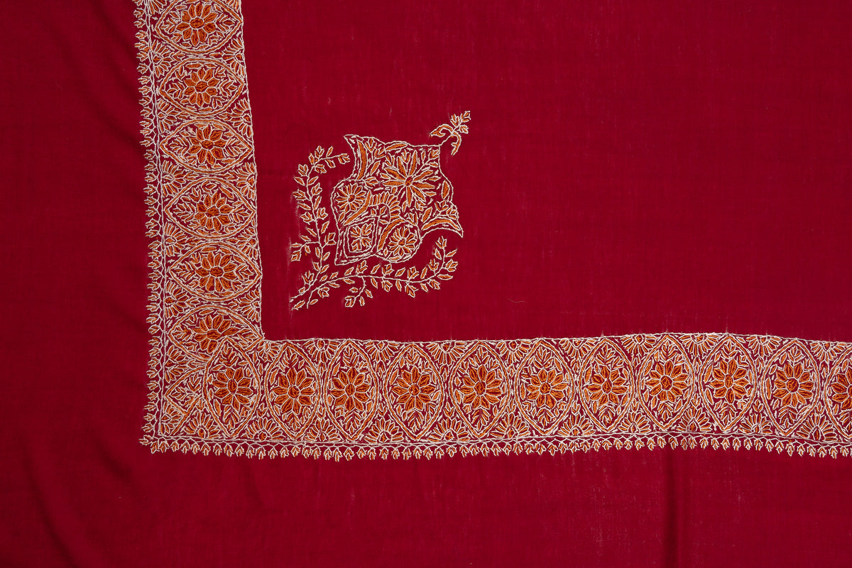 Flat corner detail of a crimson rumal with a gold-and-ivory floral border and a separate floral medallion