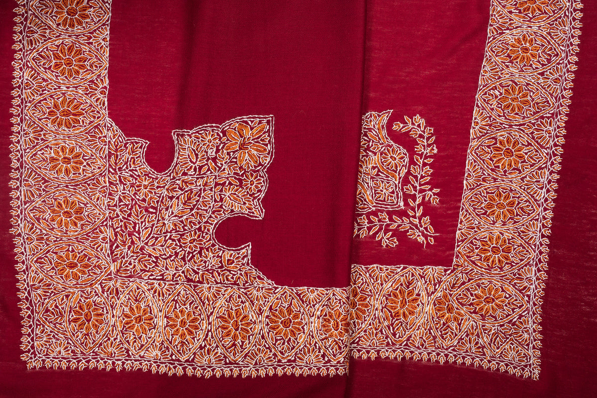 Crimson rumal laid in folds, showing its broad gold-and-ivory floral border and contrasting corner motifs