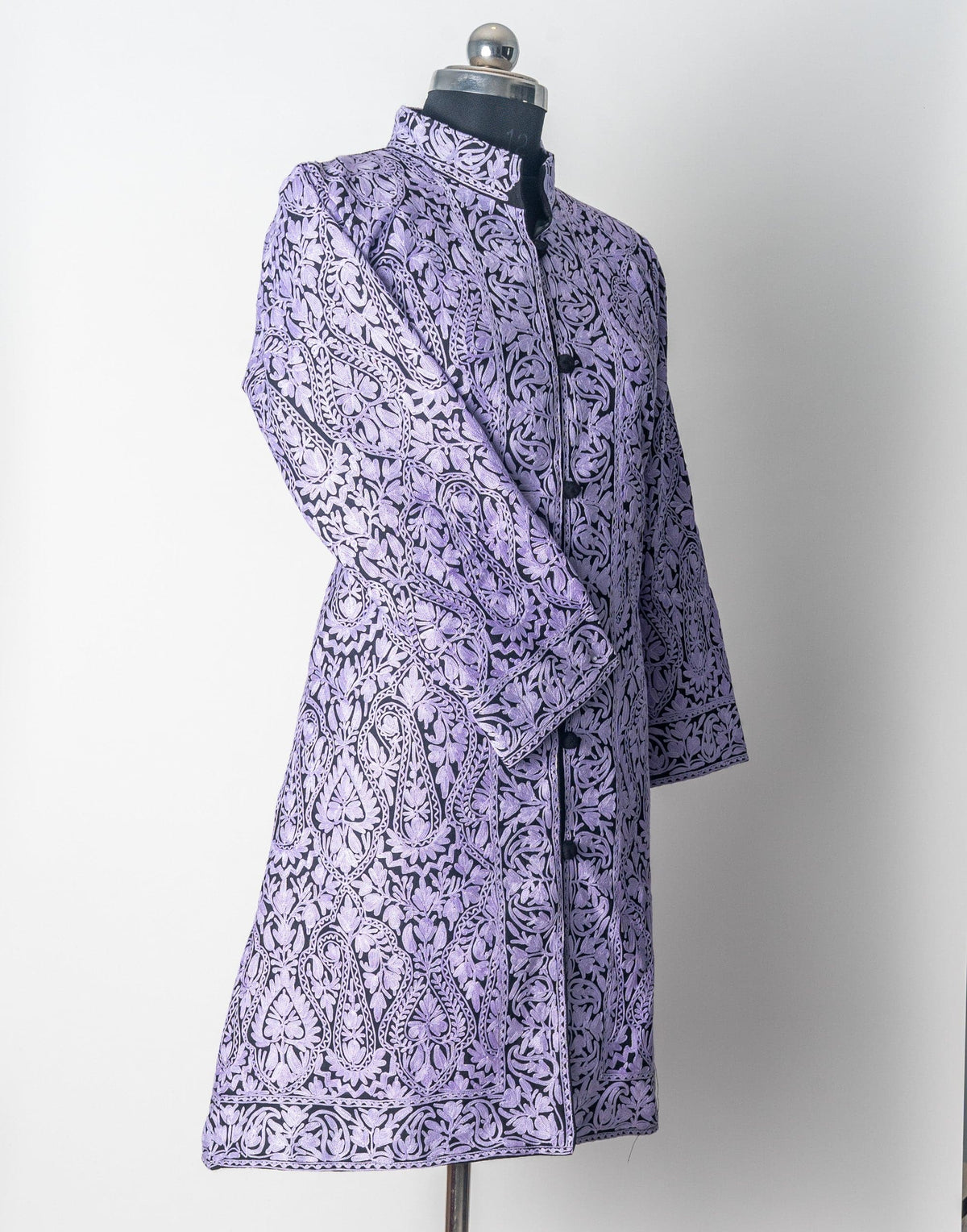 Three-quarter front of the black wool Aari jacket on a mannequin, densely covered in pale lilac floral paisleys.