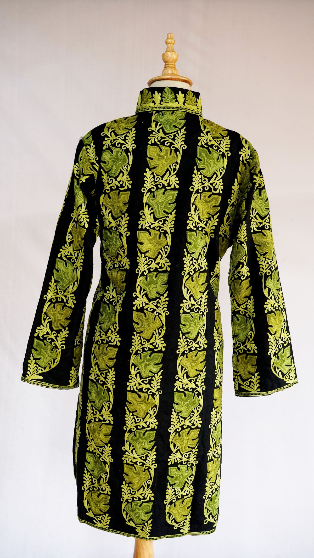 Back of a black jacket with chartreuse leaves and curling vines arranged in vertical embroidered bands.