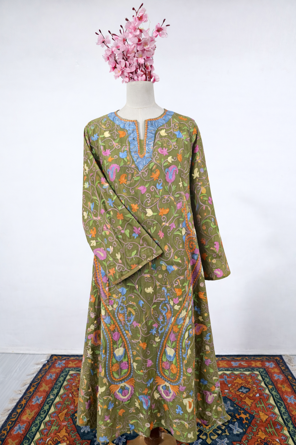 Mannequin wearing a long, patterned dress with a colorful top on a white background