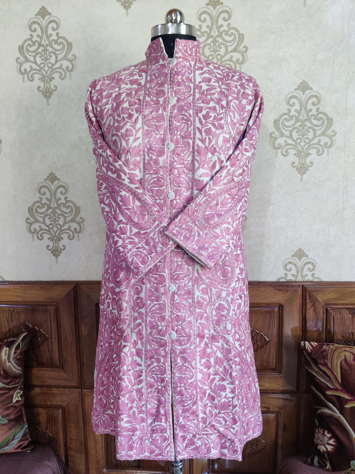 Cream and pink Aari jacket on a mannequin with crossed sleeves, pale buttons and scrolling floral borders