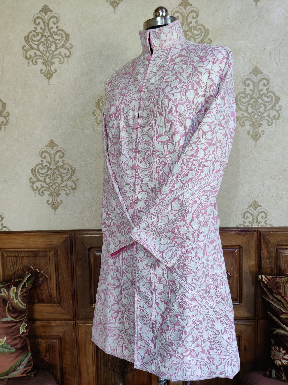 Angled full view of the pale-pink jacket with white leafy vines, paisleys and patterned front borders.