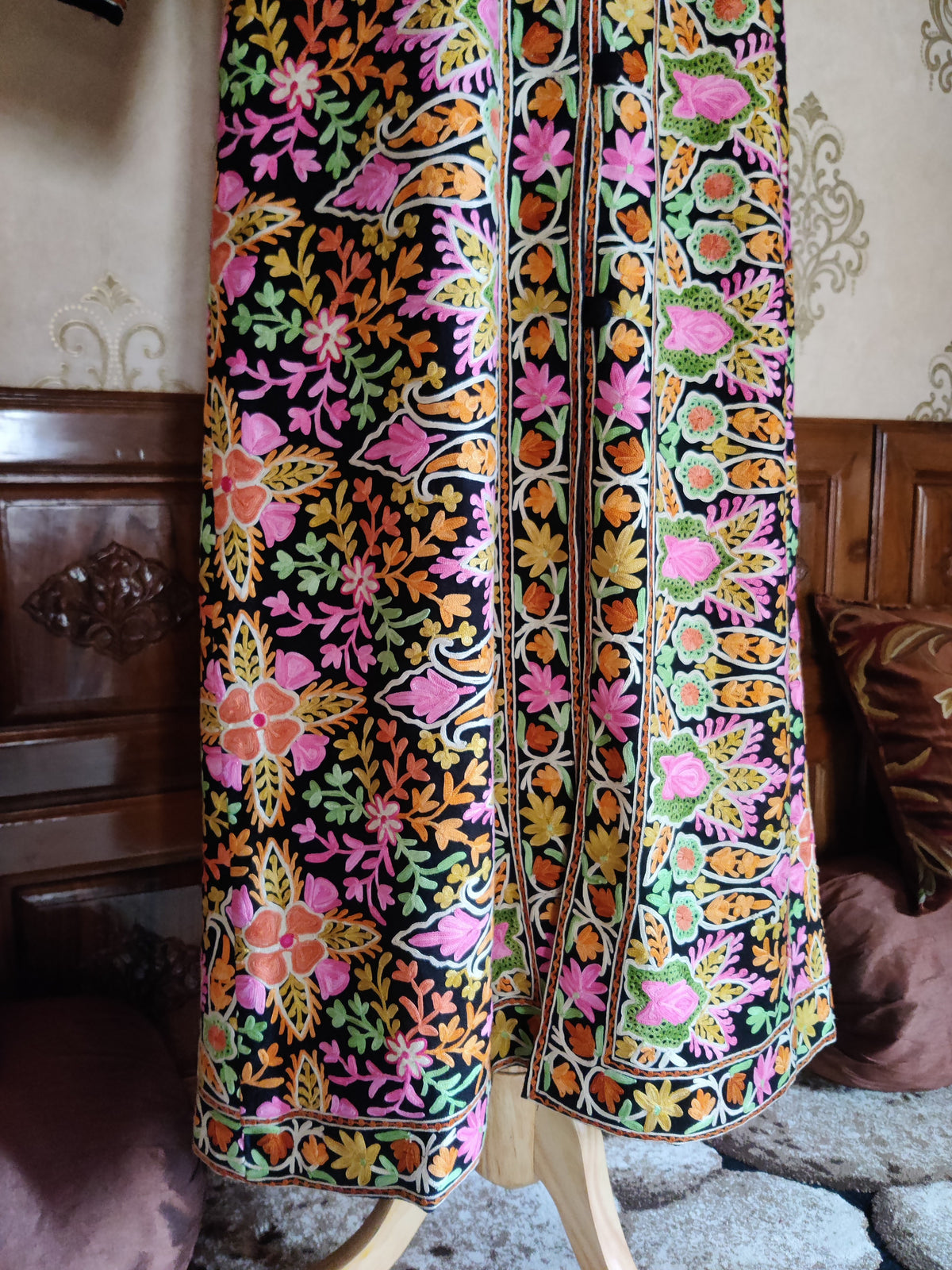 Lower front of a long black Aari jacket with colourful floral panels, embroidered front edges and a floral hem